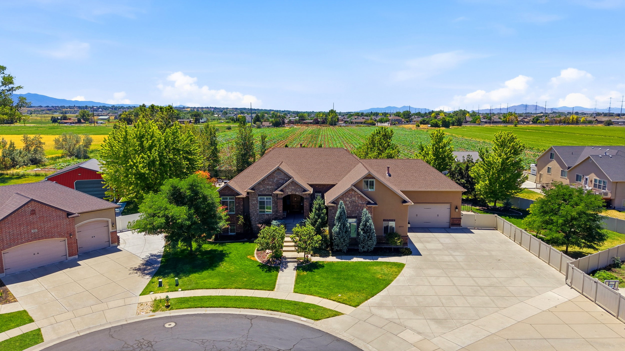 Expansive property featuring a multi-car driveway, mature landscaping, and a brick and stucco exterior