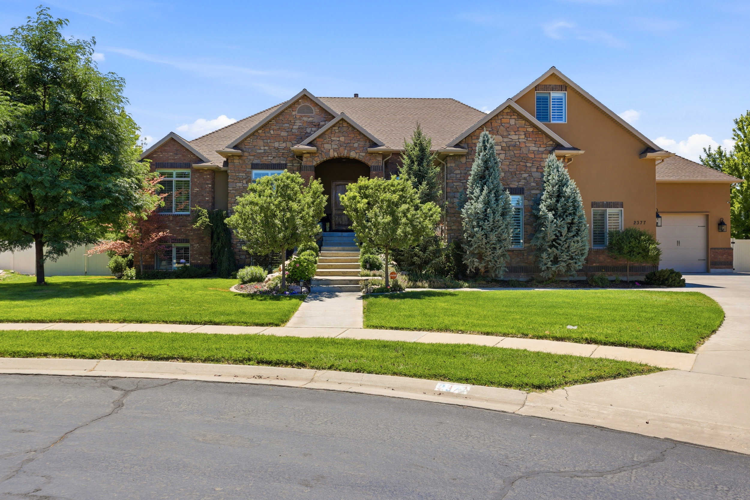 Stone and stucco exterior featuring a gabled roofline and attached garage