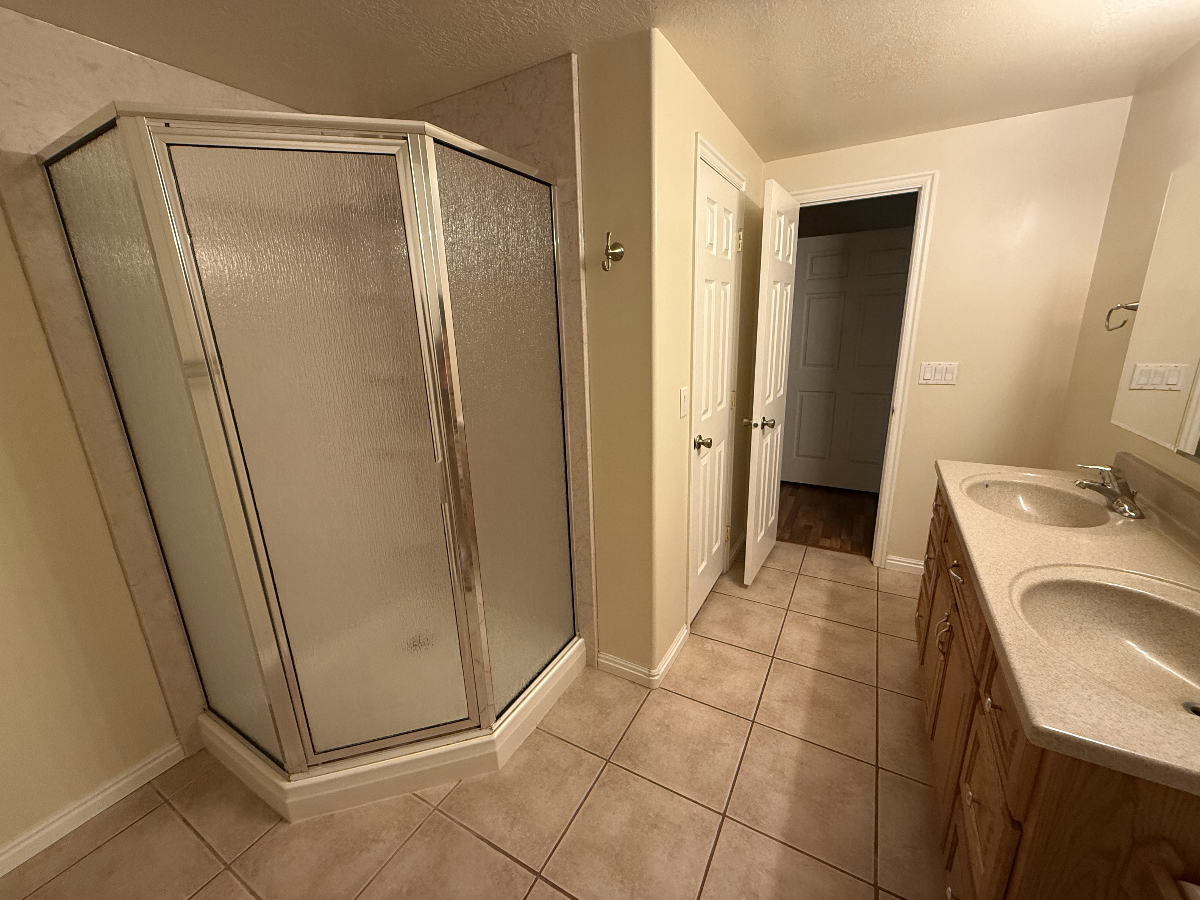 Shower enclosure with frosted glass panels, accompanied by a double vanity featuring integrated sinks and a neutral countertop