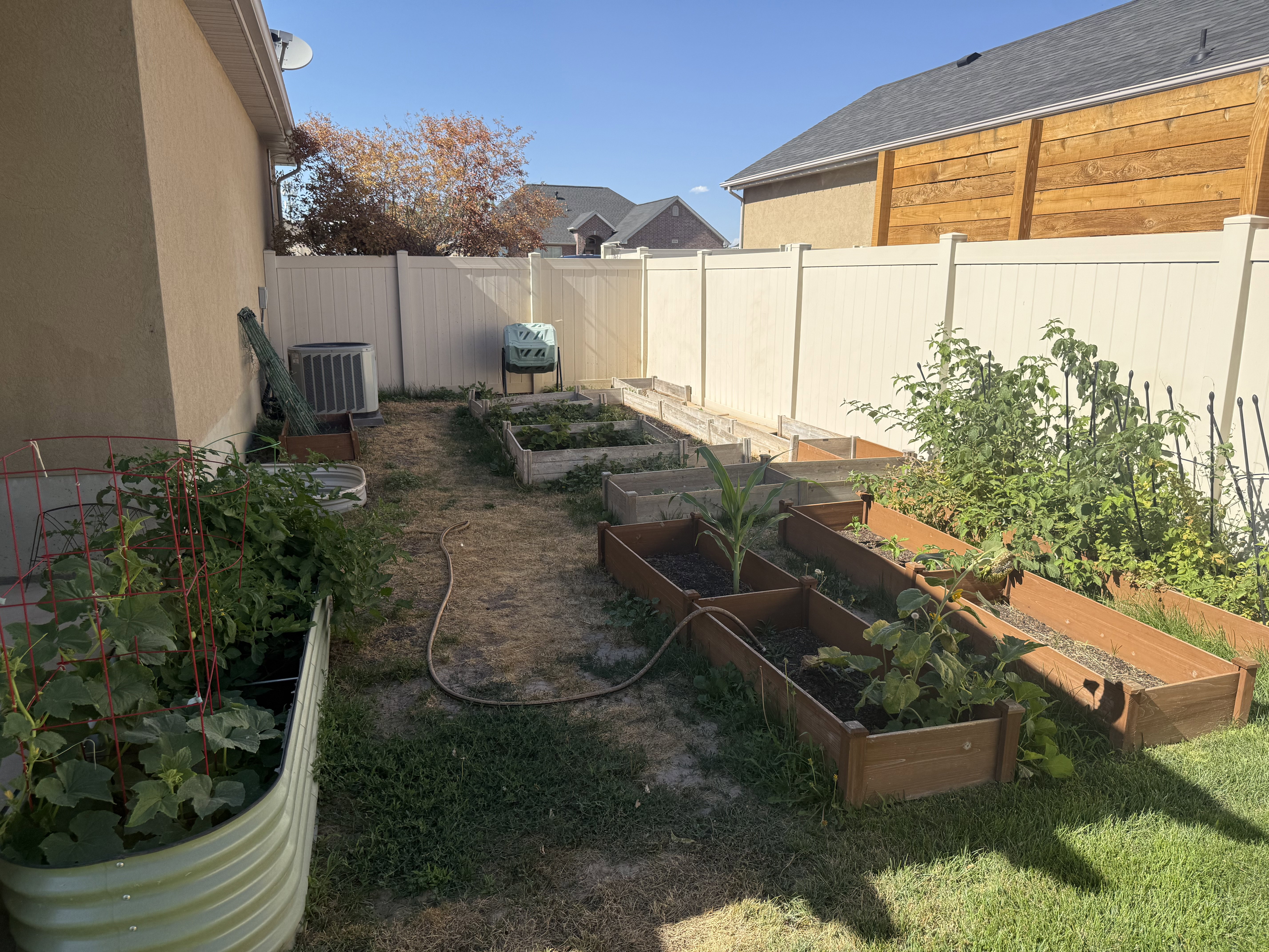 Backyard space featuring multiple raised garden beds, a corrugated metal planter, and an air conditioning unit