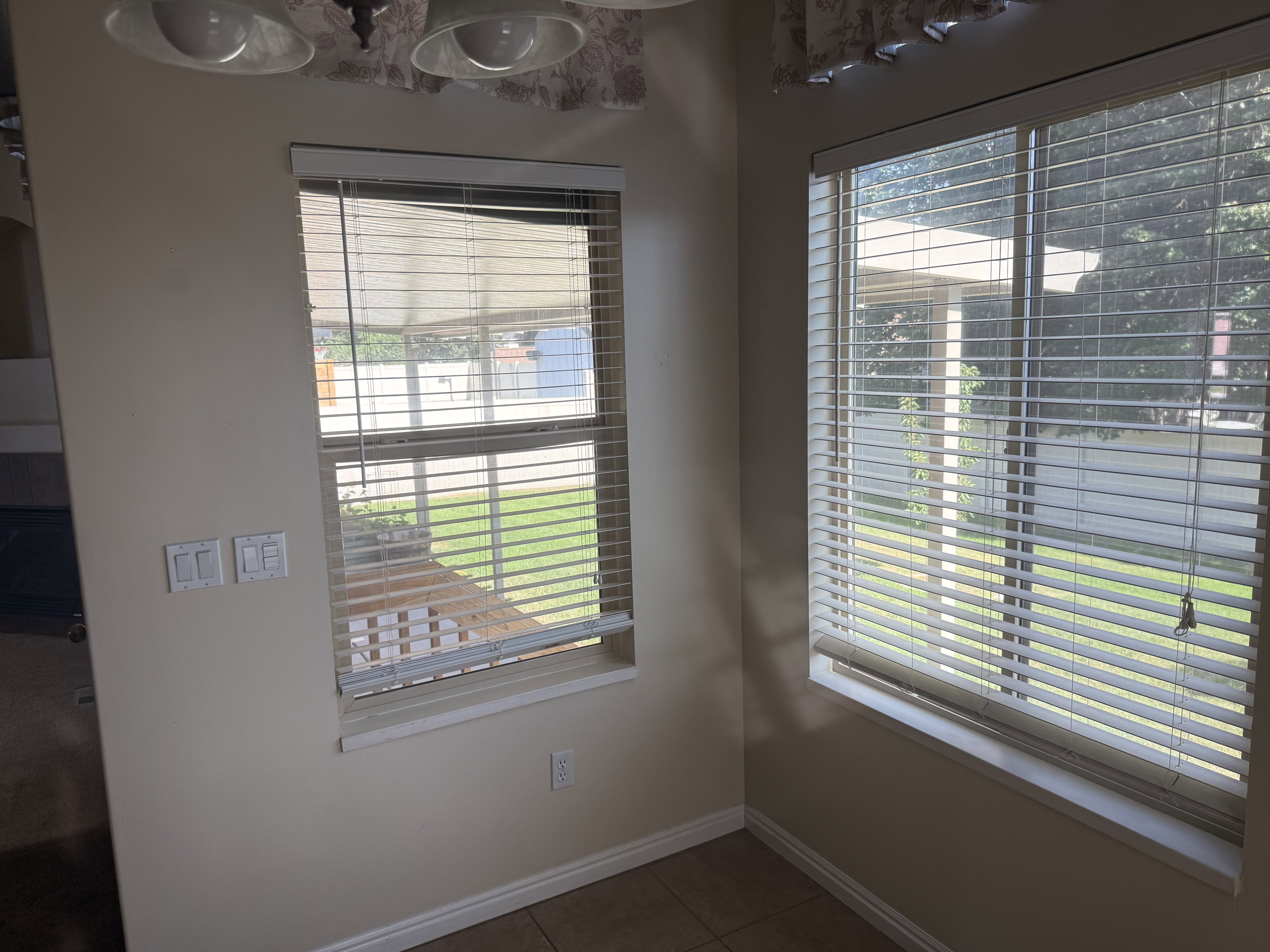 Corner window composition featuring a larger window with horizontal blinds and a smaller window with both horizontal blinds and a privacy shade