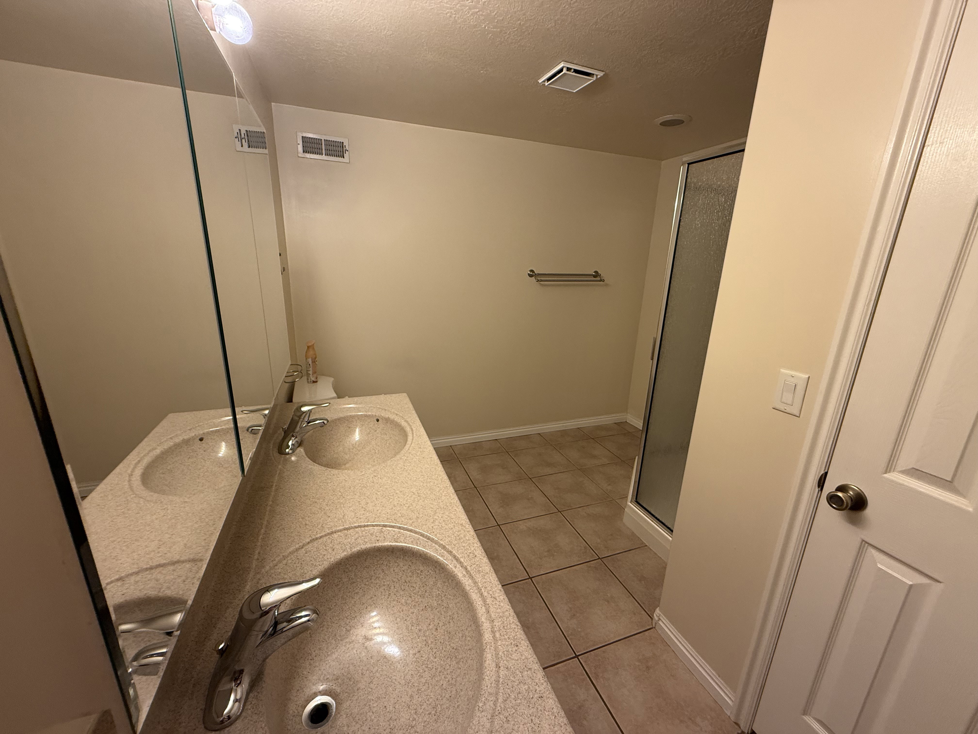 Dual basin vanity with speckled countertop, chrome fixtures, and a frameless mirror