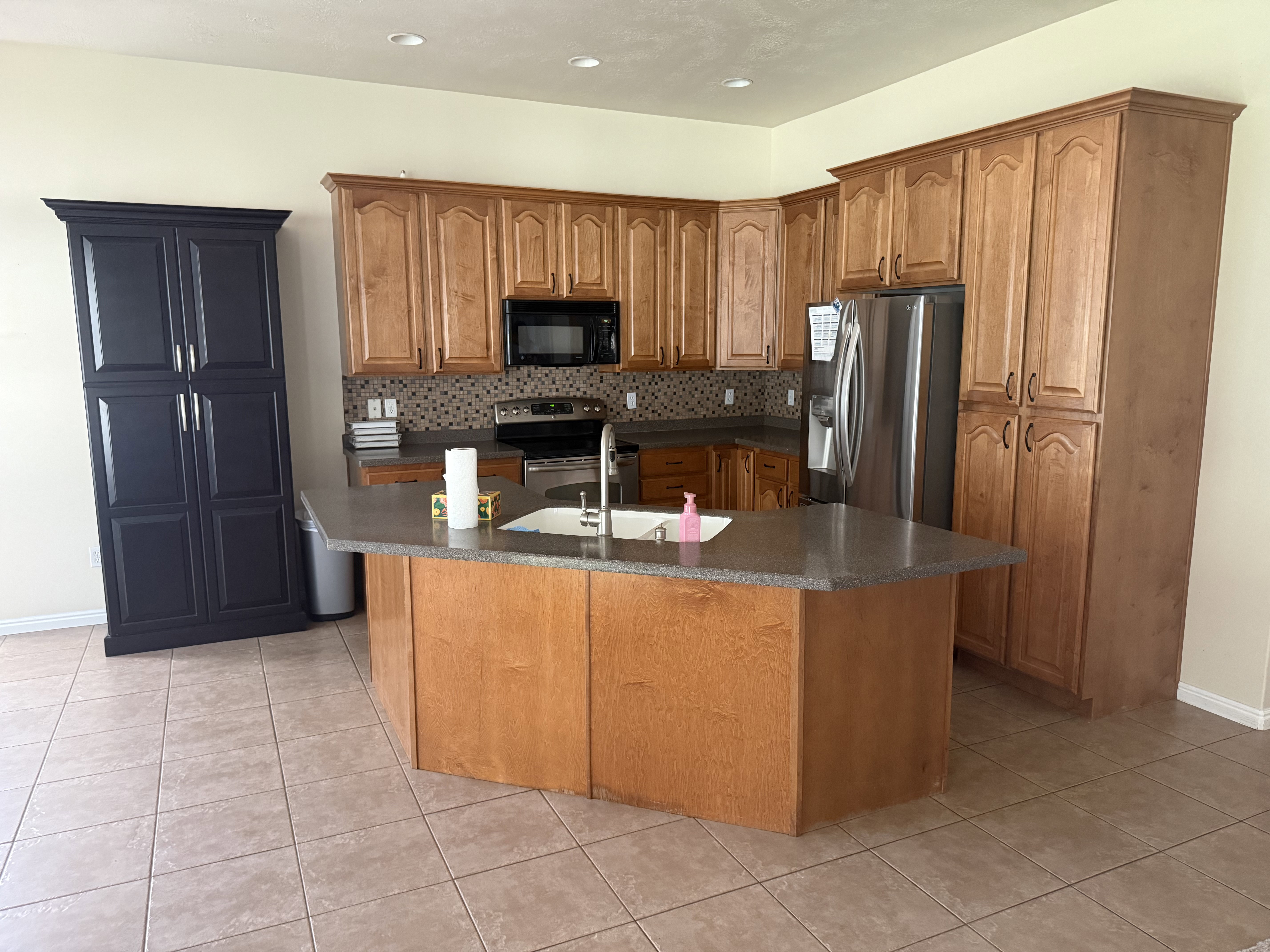 Kitchen featuring wood cabinetry, stone-look countertops, and a mosaic tile backsplash
