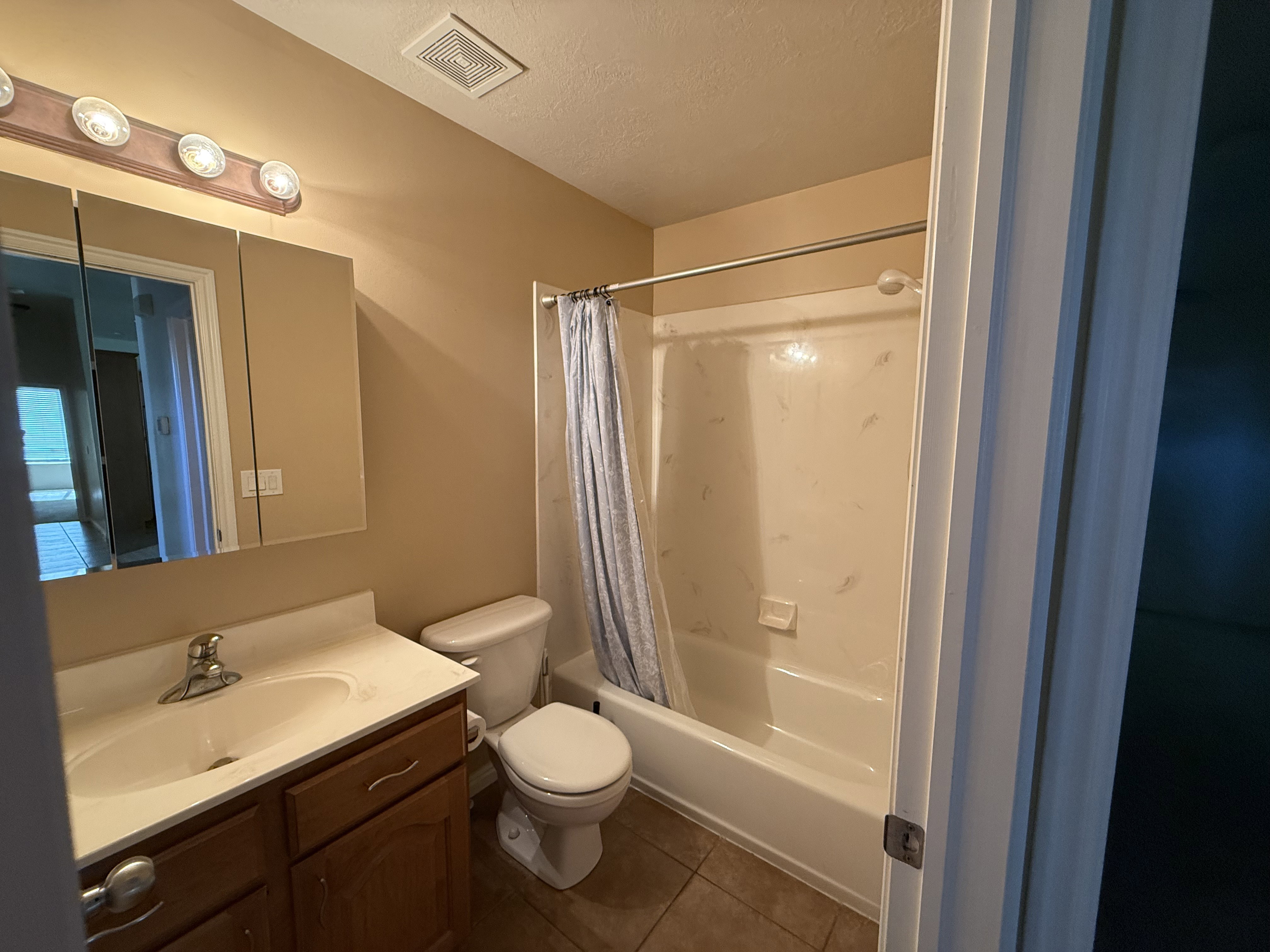 Full bathroom featuring a single vanity with wood-finish cabinetry, a white countertop with integrated sink, and a combination shower and tub