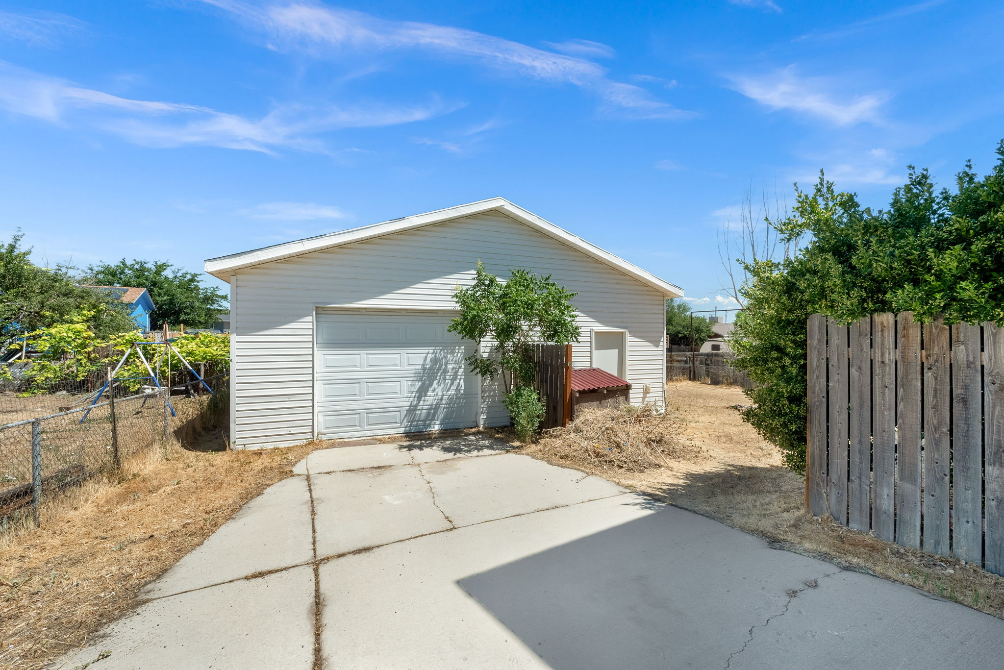 Detached garage with horizontal siding, a paneled garage door, and a side access door