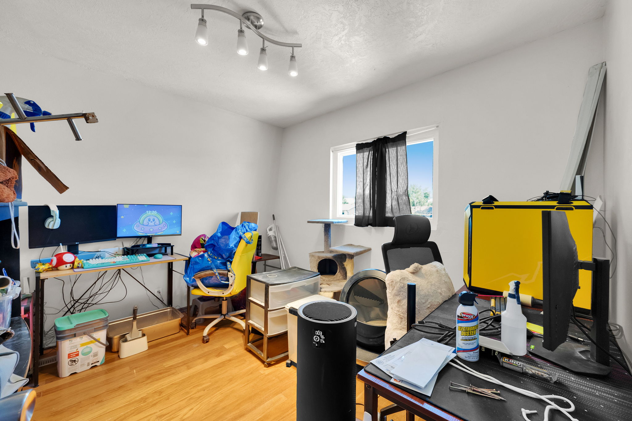Room featuring wood-finish flooring, a single window with dark drapes, and white painted walls