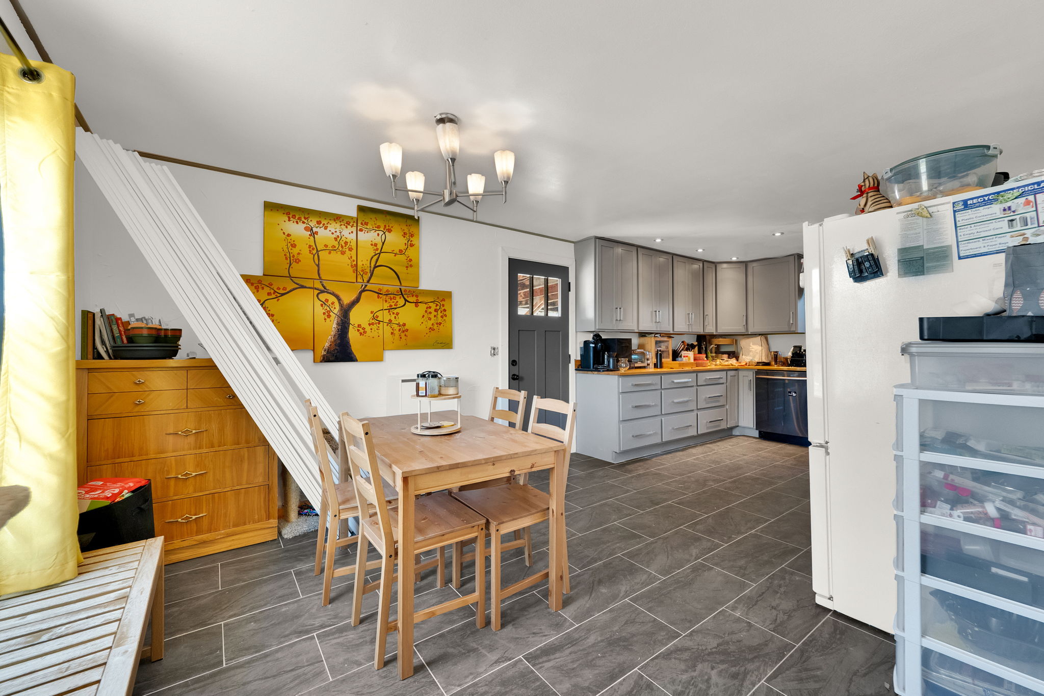 Open-concept kitchen and dining area featuring slate-style tile flooring, light gray cabinetry, wood-finish countertops, and recessed lighting