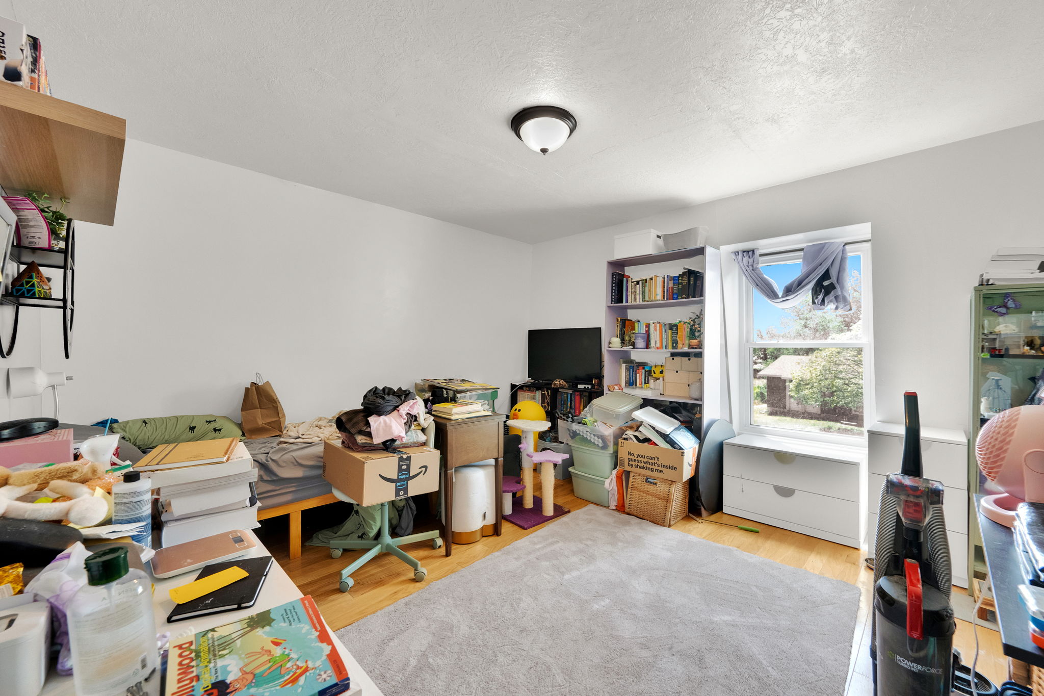 Spacious room featuring light wood-finish flooring, white walls, and a window providing natural light
