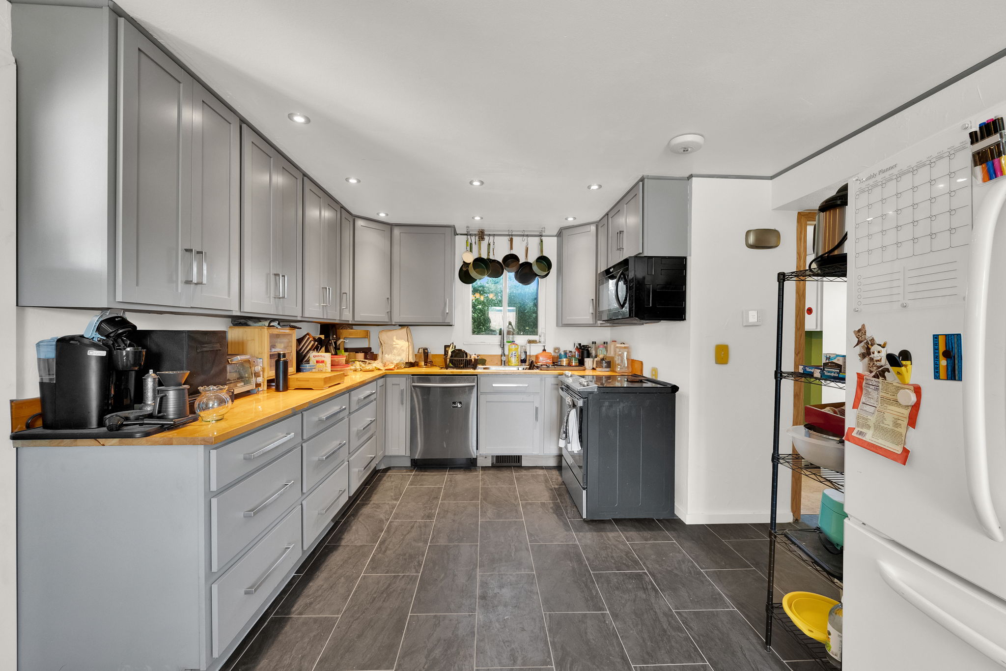 Kitchen featuring extensive gray cabinetry, wood-finish countertops, stainless steel dishwasher, black range, and recessed lighting