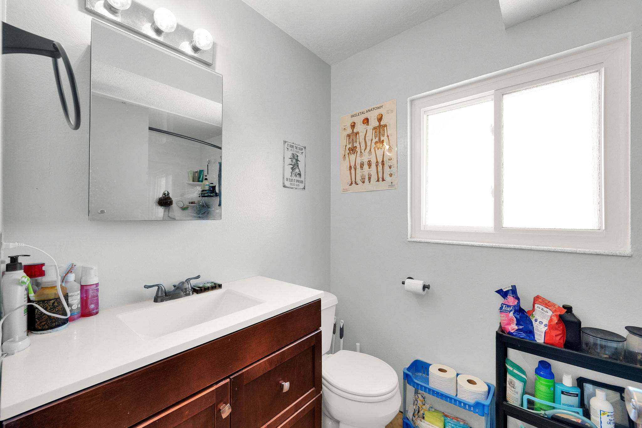 Bathroom featuring a wood-finish vanity with an integrated sink, a medicine cabinet, and a window with privacy glass