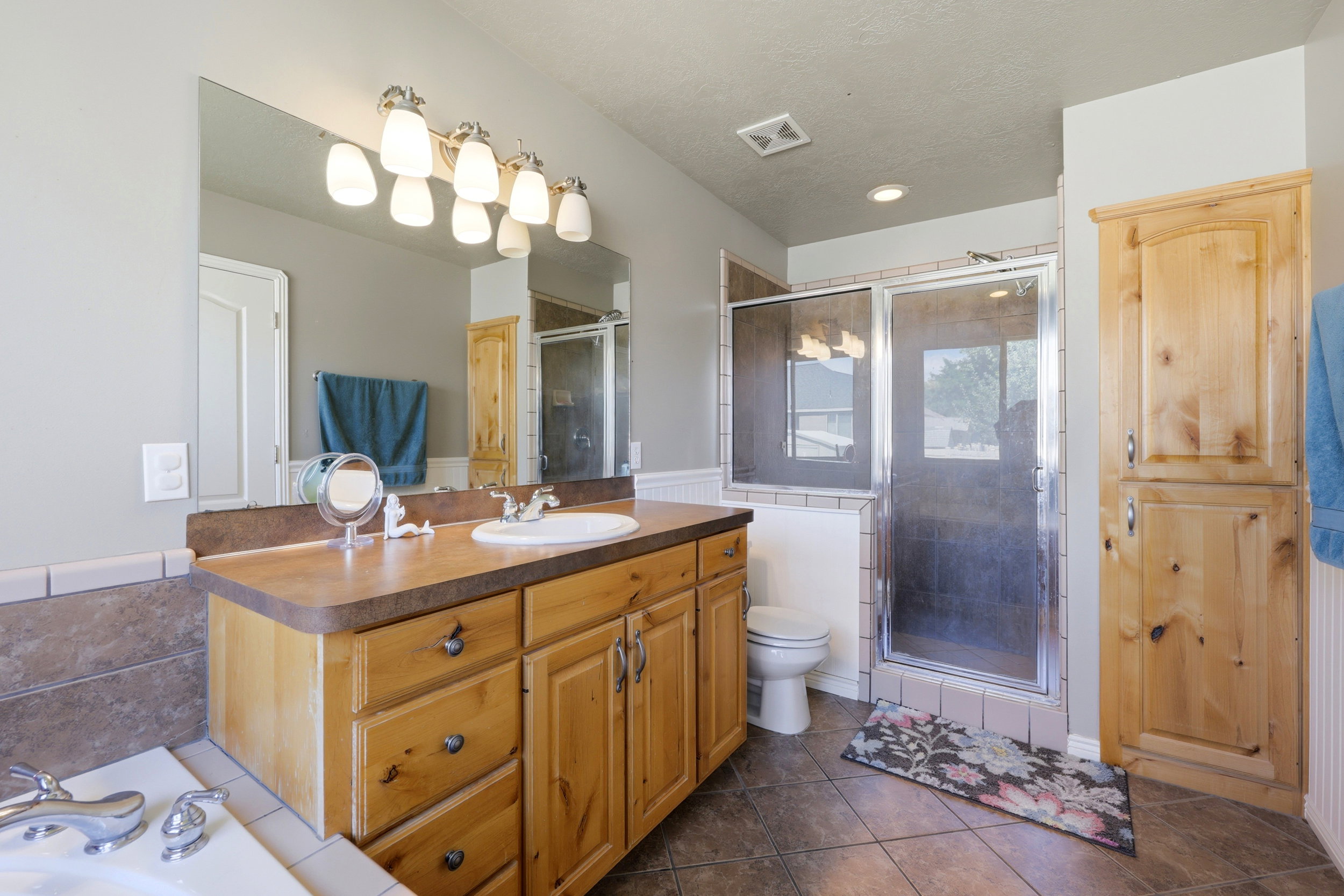 Primary bathroom featuring a wood-finish vanity with an integrated sink and a large wall mirror