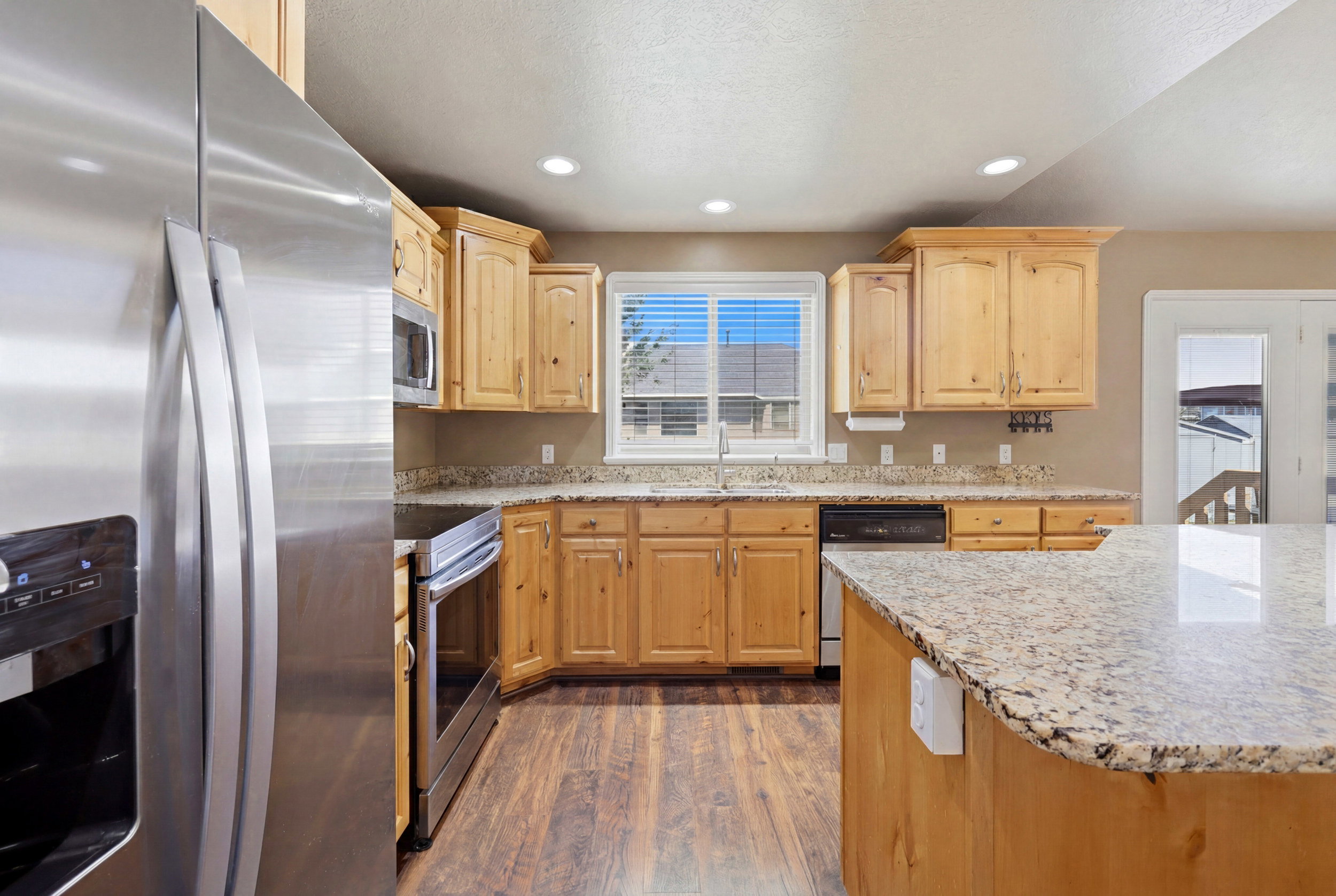 Kitchen featuring wood-finish flooring, light wood cabinetry, and granite countertops
