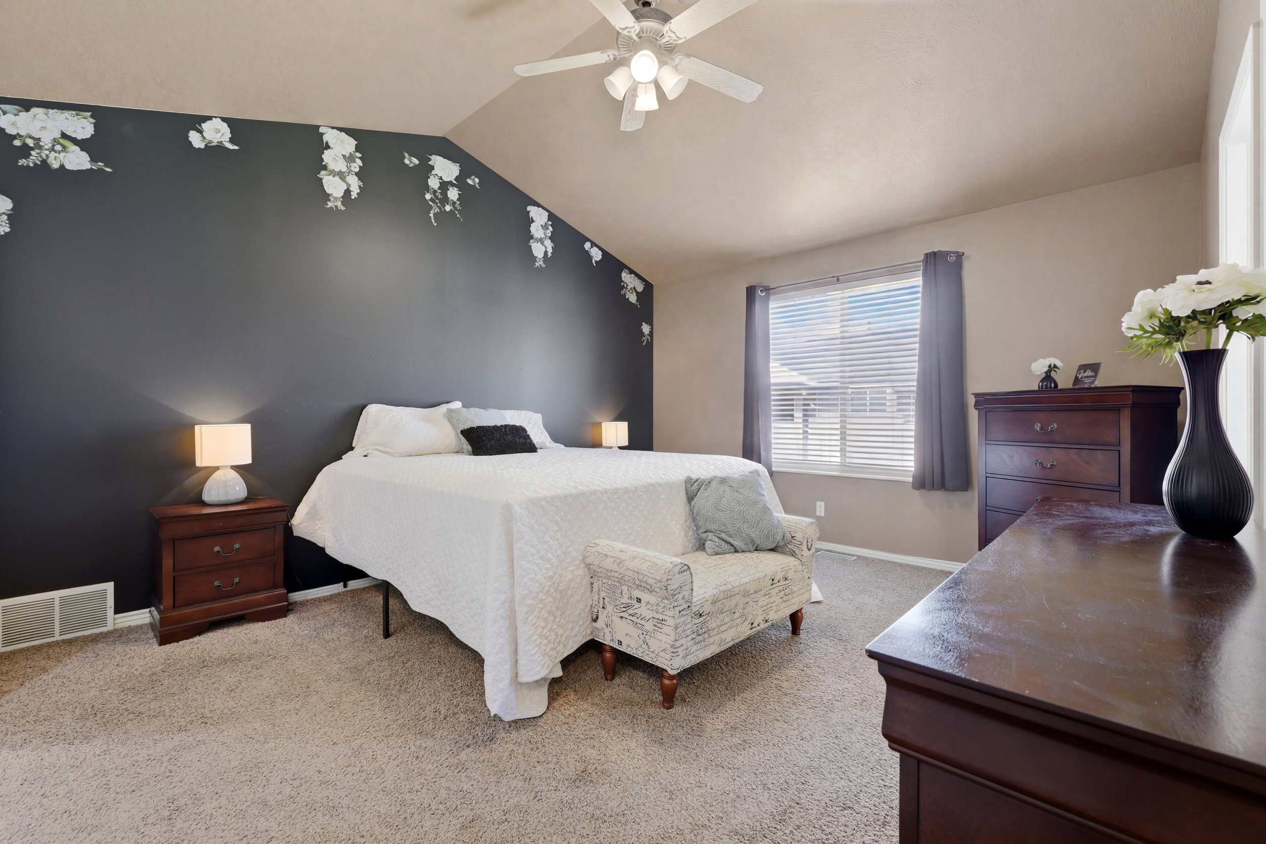 Vaulted ceiling bedroom with a prominent dark accent wall featuring light floral detailing
