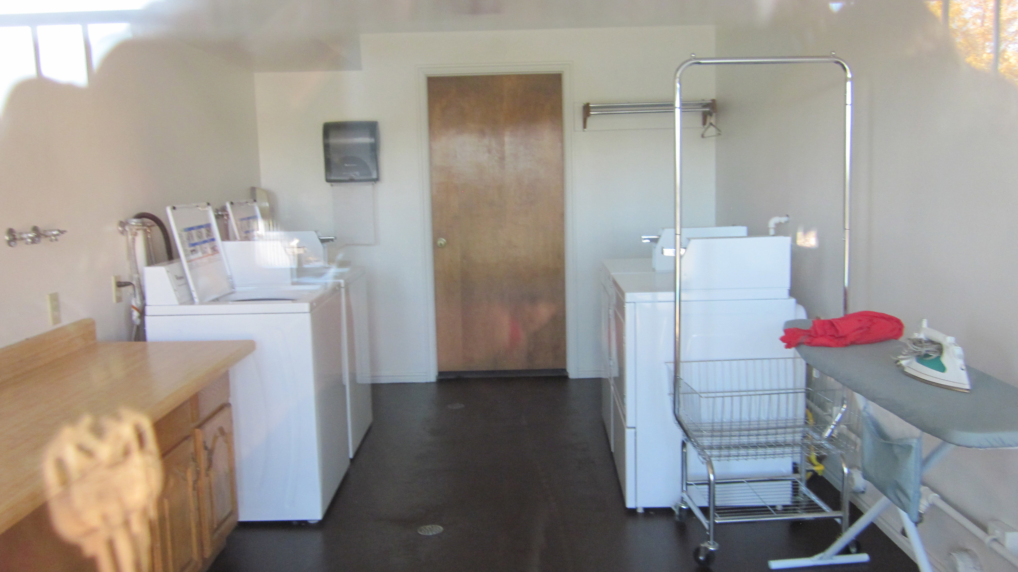 Dedicated laundry facility featuring multiple washing machines, dryers, a built-in counter, and cabinet storage