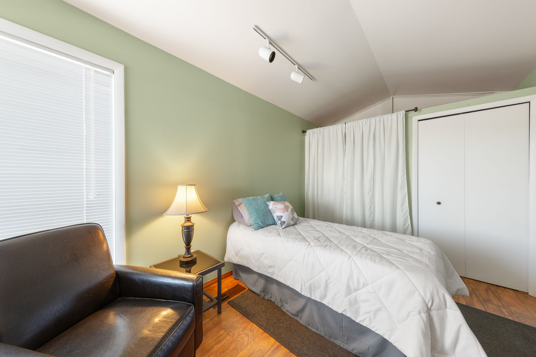 Interior space featuring light green wall paint, wood-finish flooring, and track lighting