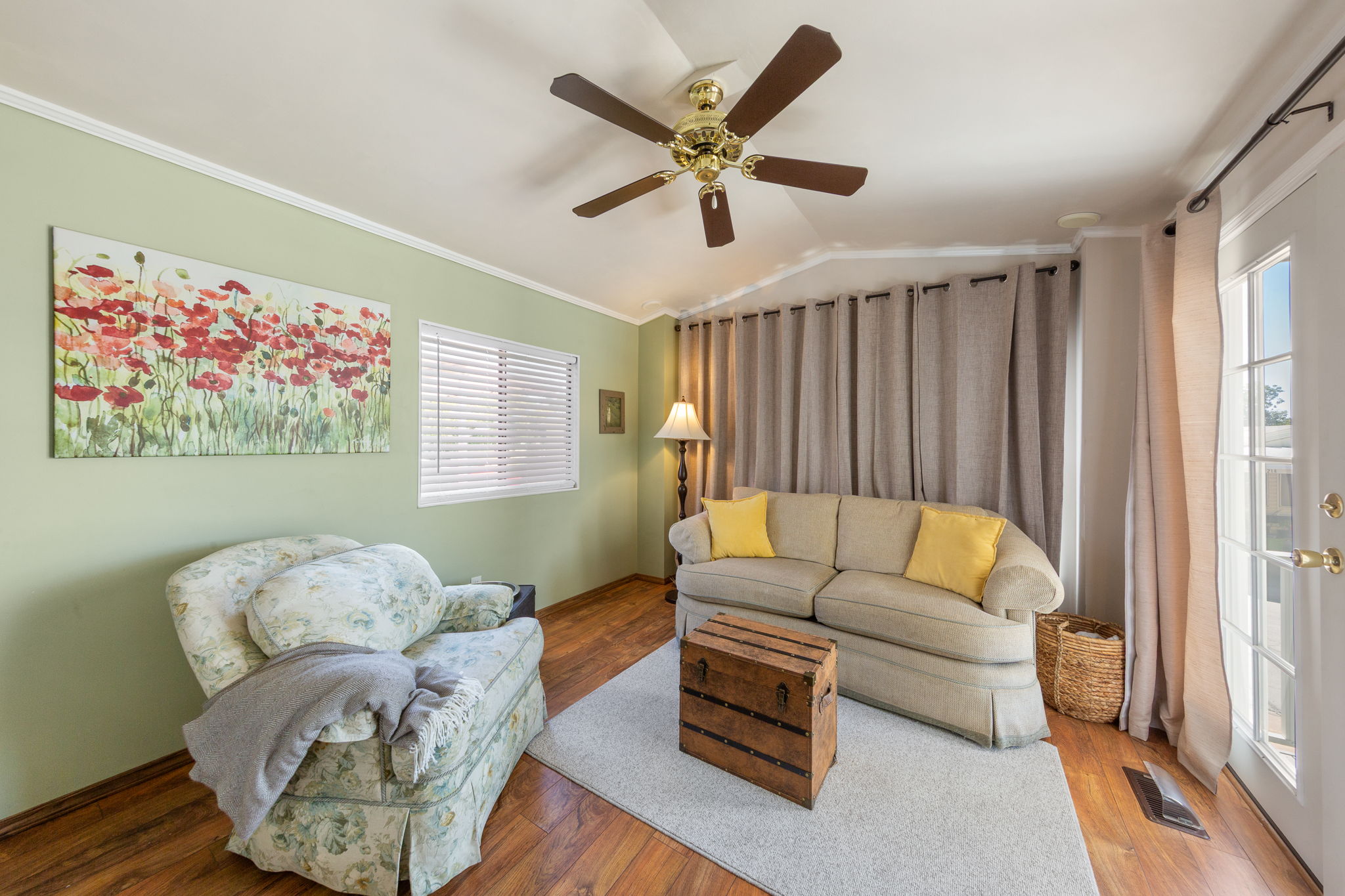 Living area featuring wood-finish flooring, a ceiling fan with integrated lighting, and light green walls