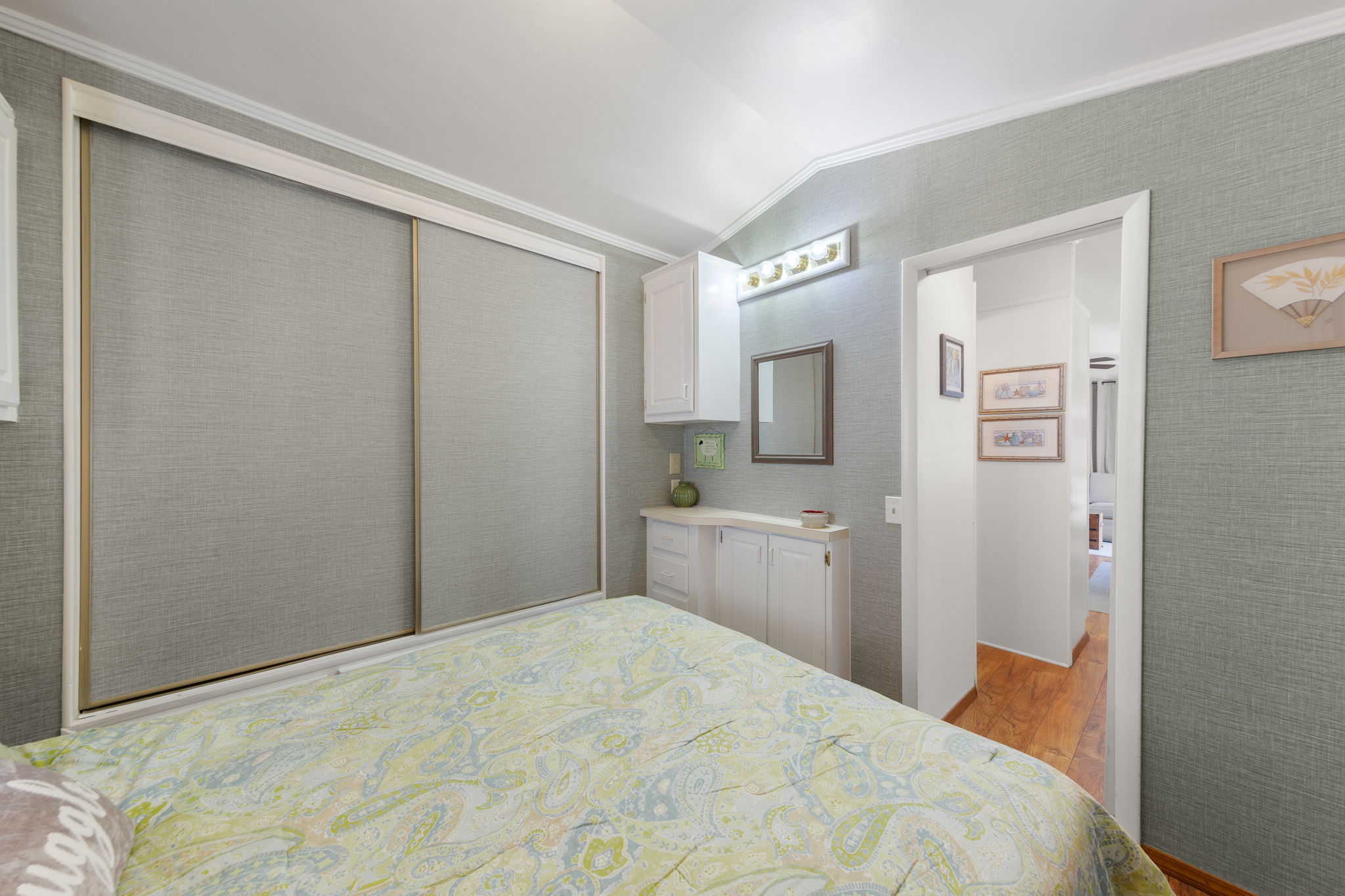 Bedroom featuring light gray textured wall coverings, white crown molding, and sliding closet doors