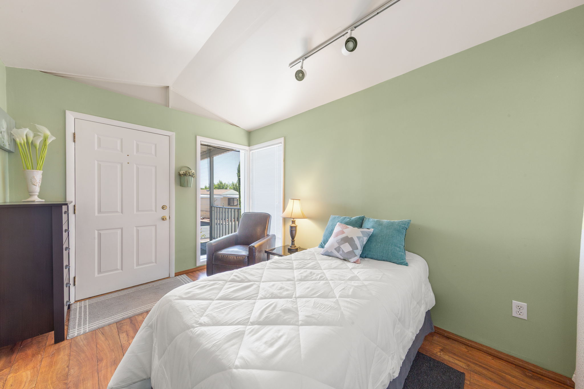 Interior space featuring a white paneled entry door, wood-finish flooring, and a sliding glass door providing exterior access