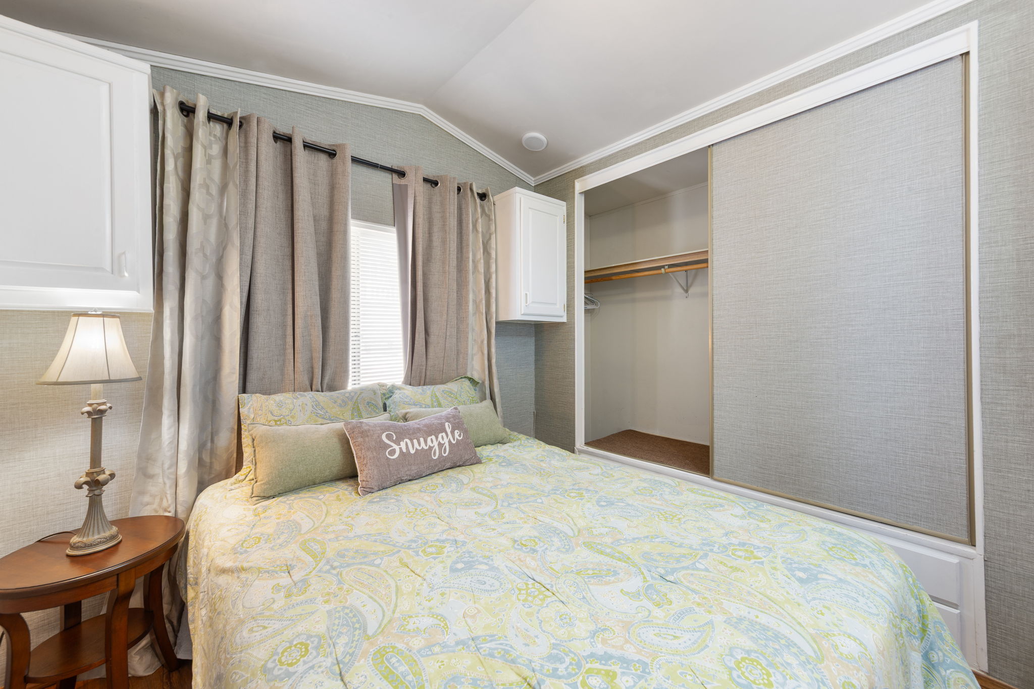 Bedroom featuring a built-in closet with sliding fabric doors, a wall-mounted cabinet, and textured wall coverings