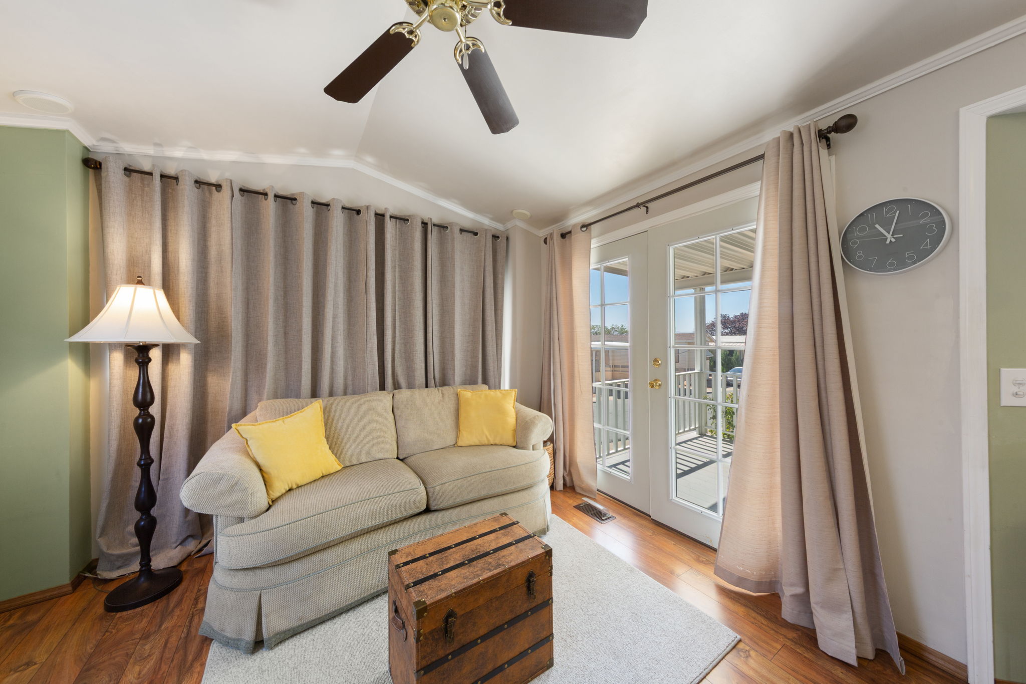 Living area featuring wood-finish flooring, a ceiling fan, and white French doors opening to an exterior balcony