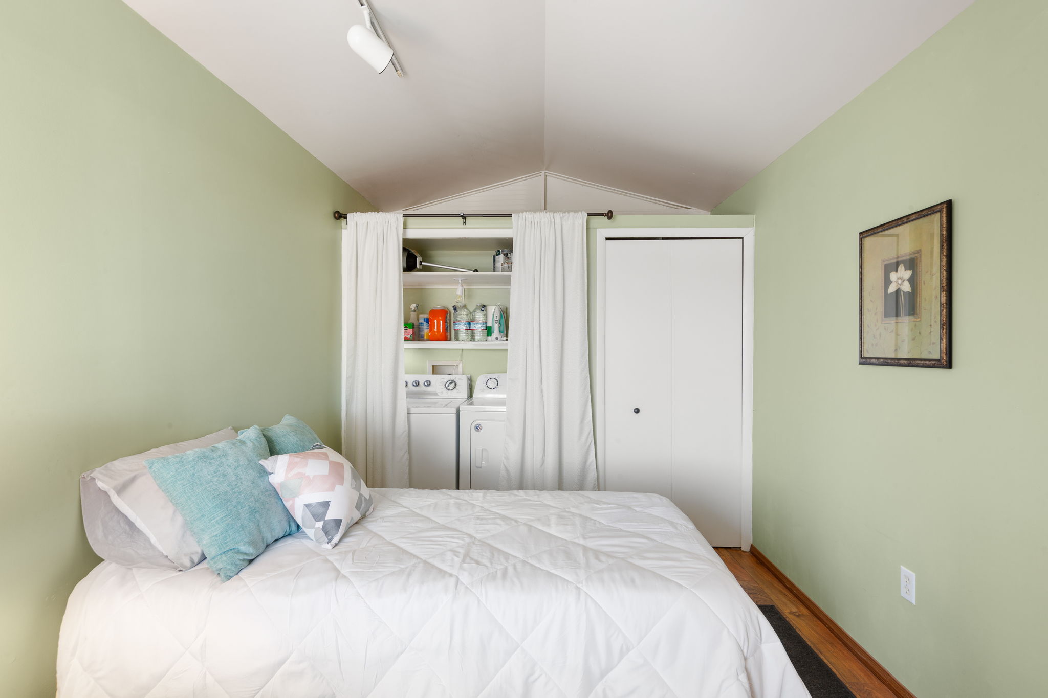 Room with vaulted ceiling, featuring track lighting and light green walls