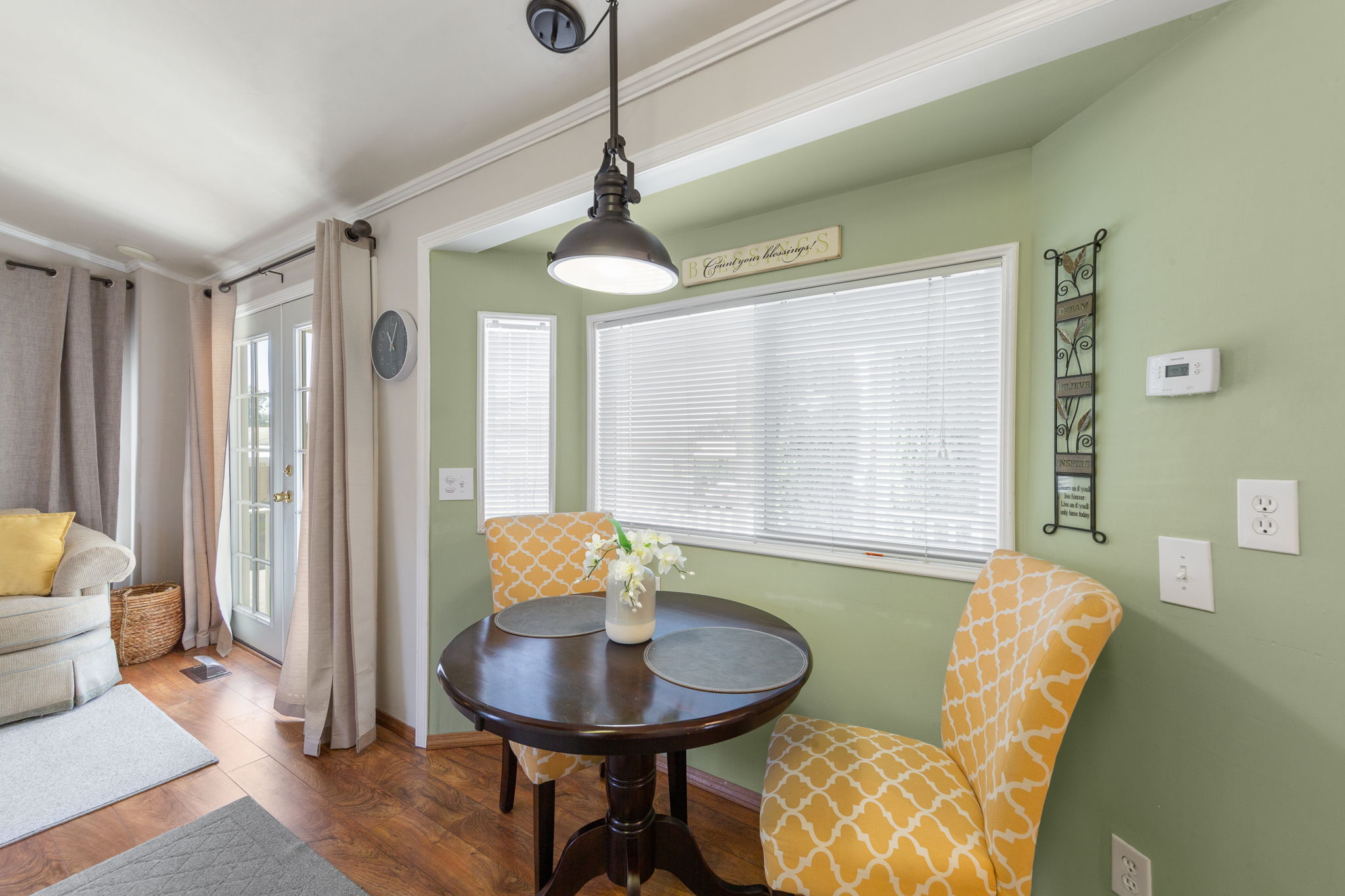 Dining area featuring wood-finish flooring, a pendant light fixture, and a large window with horizontal blinds