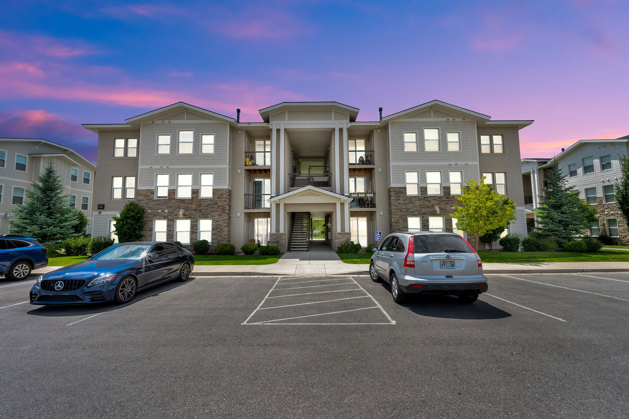 Multi-story residential building featuring light-colored siding and stone-veneer accents
