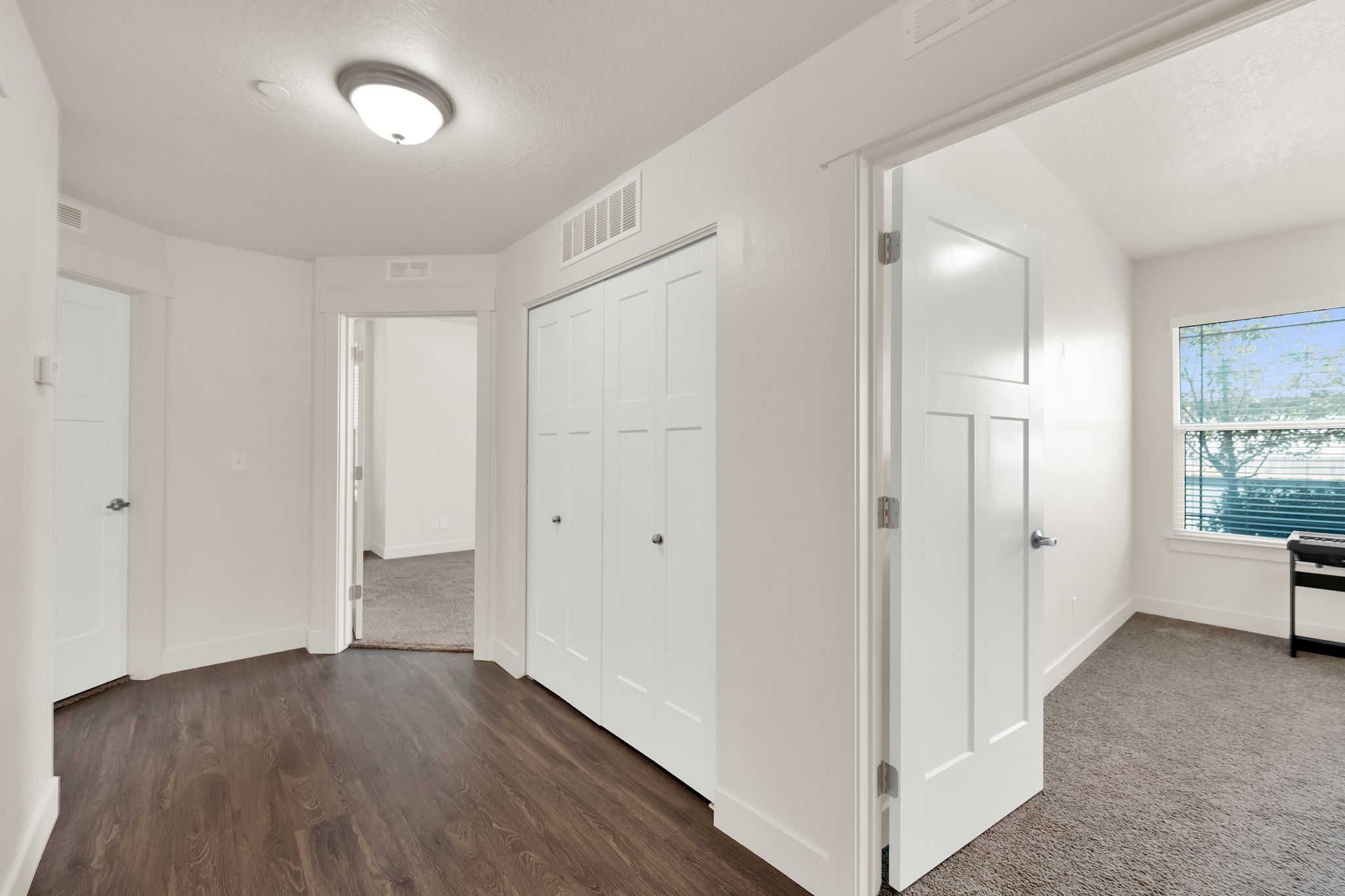 Hallway featuring wood-finish flooring, white paneled doors, and a flush mount ceiling light