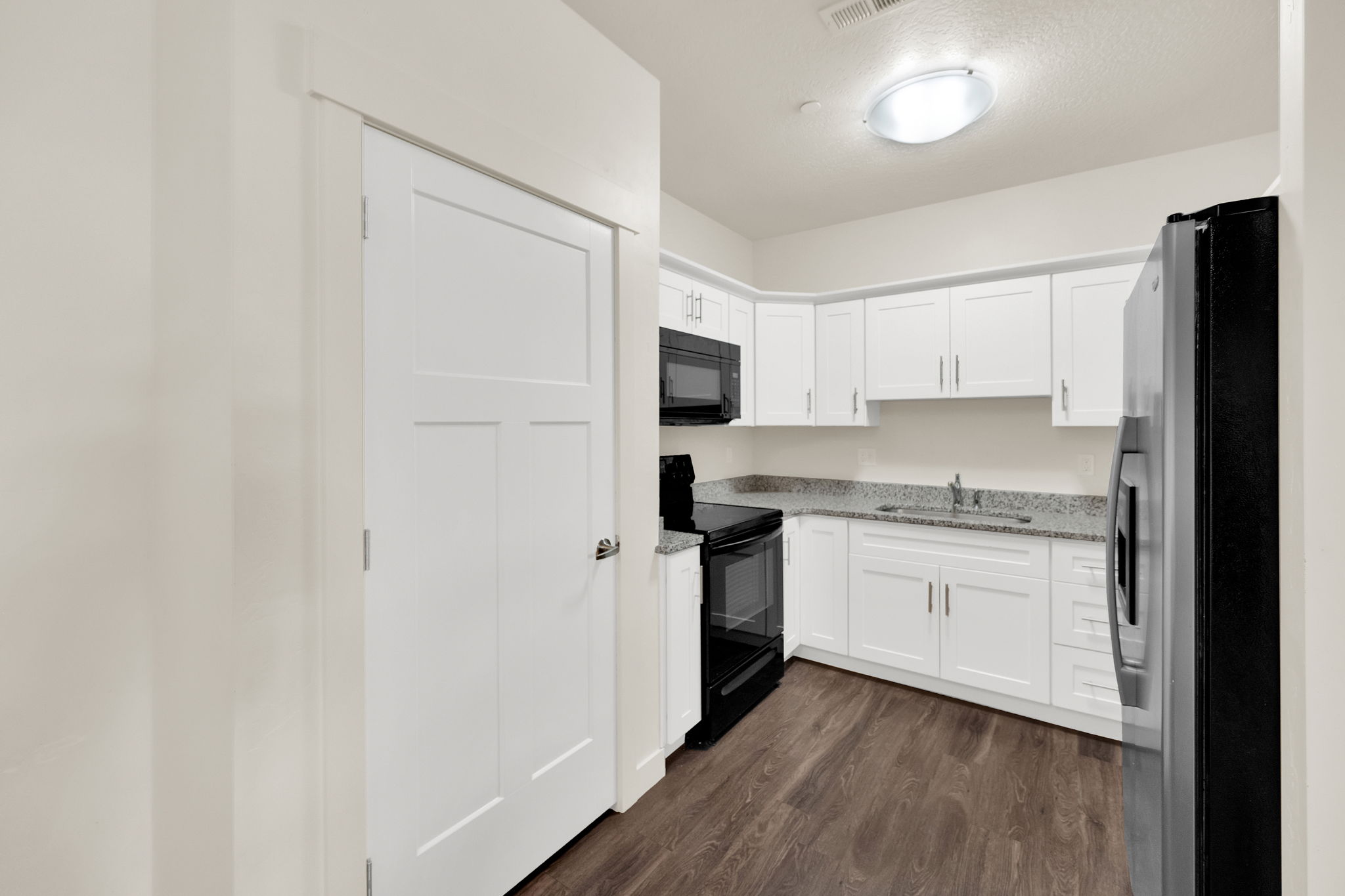 Modern kitchen featuring white cabinetry and dark wood-finish flooring