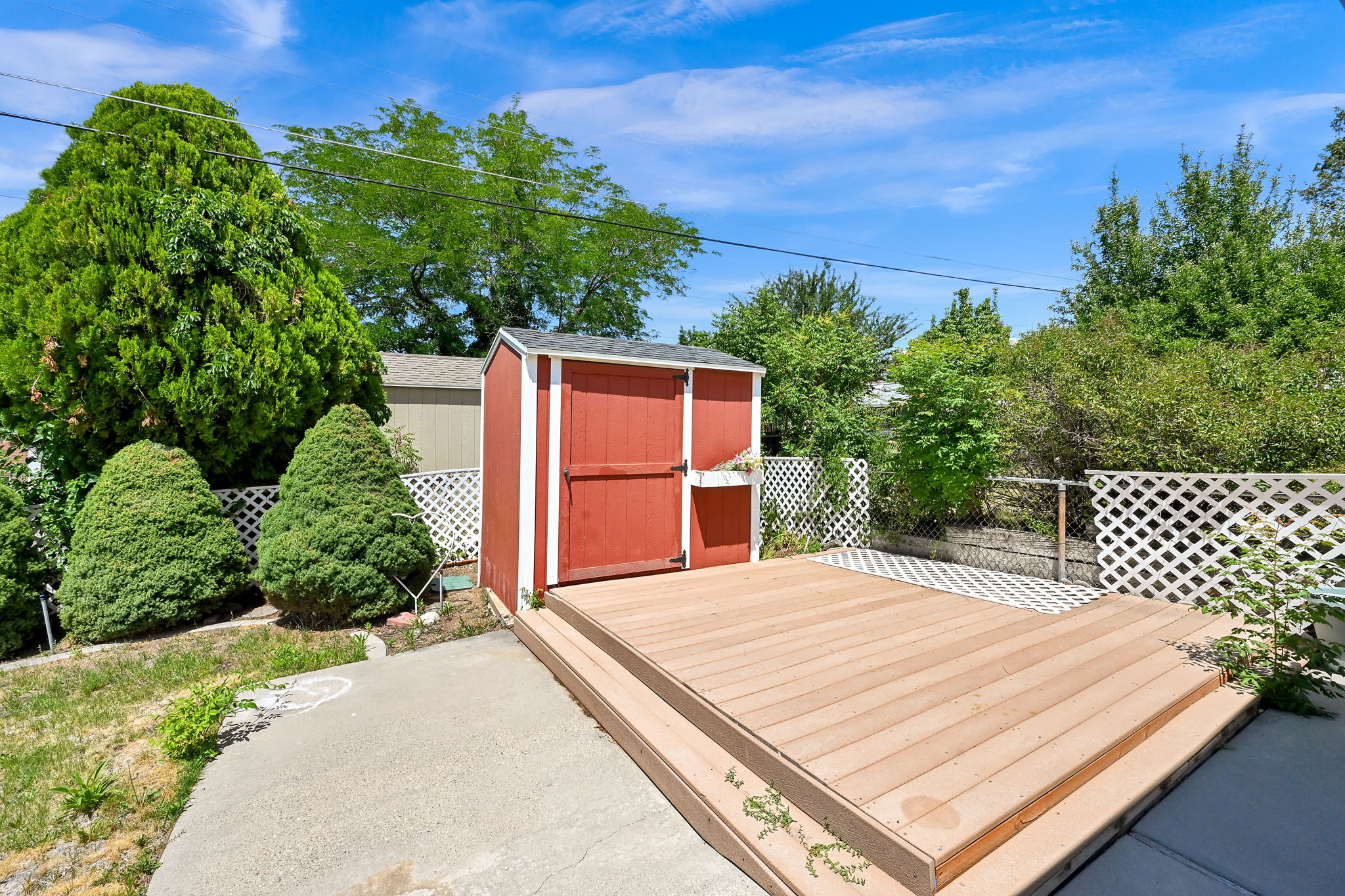 Outdoor wooden deck with two steps and a red storage shed