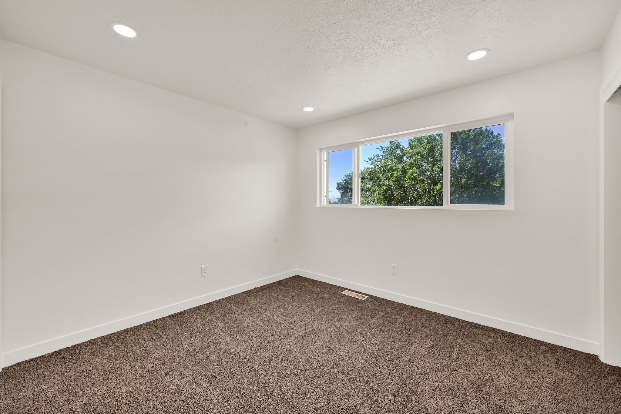 Bright interior room with recessed lighting and neutral-toned carpeting