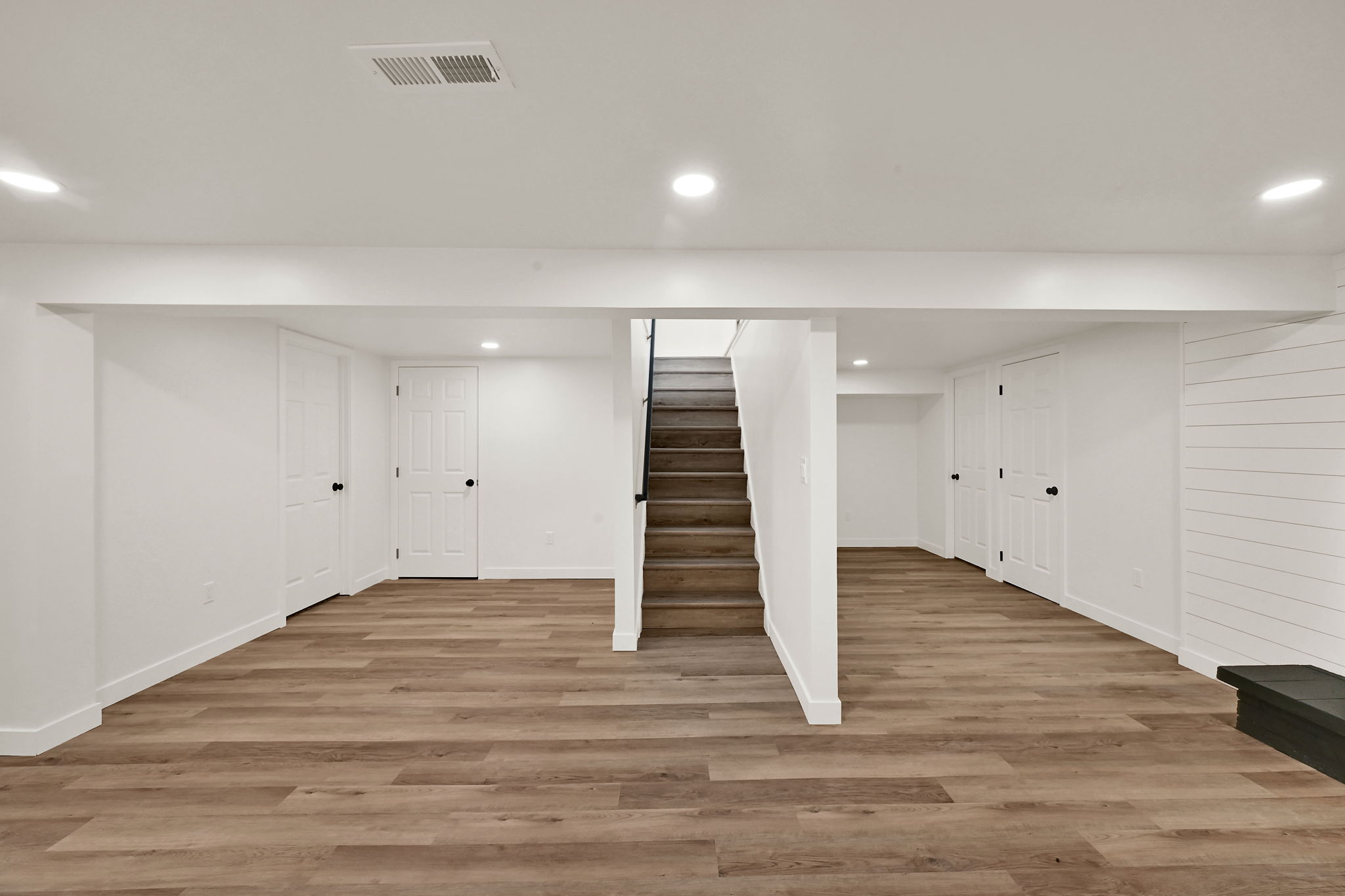 Spacious finished lower level featuring wood-finish flooring, recessed lighting, and crisp white walls