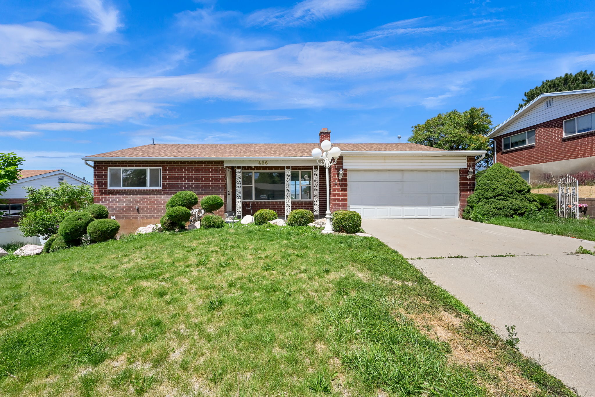Brick exterior with a peaked roofline, an attached two-car garage, and a concrete driveway