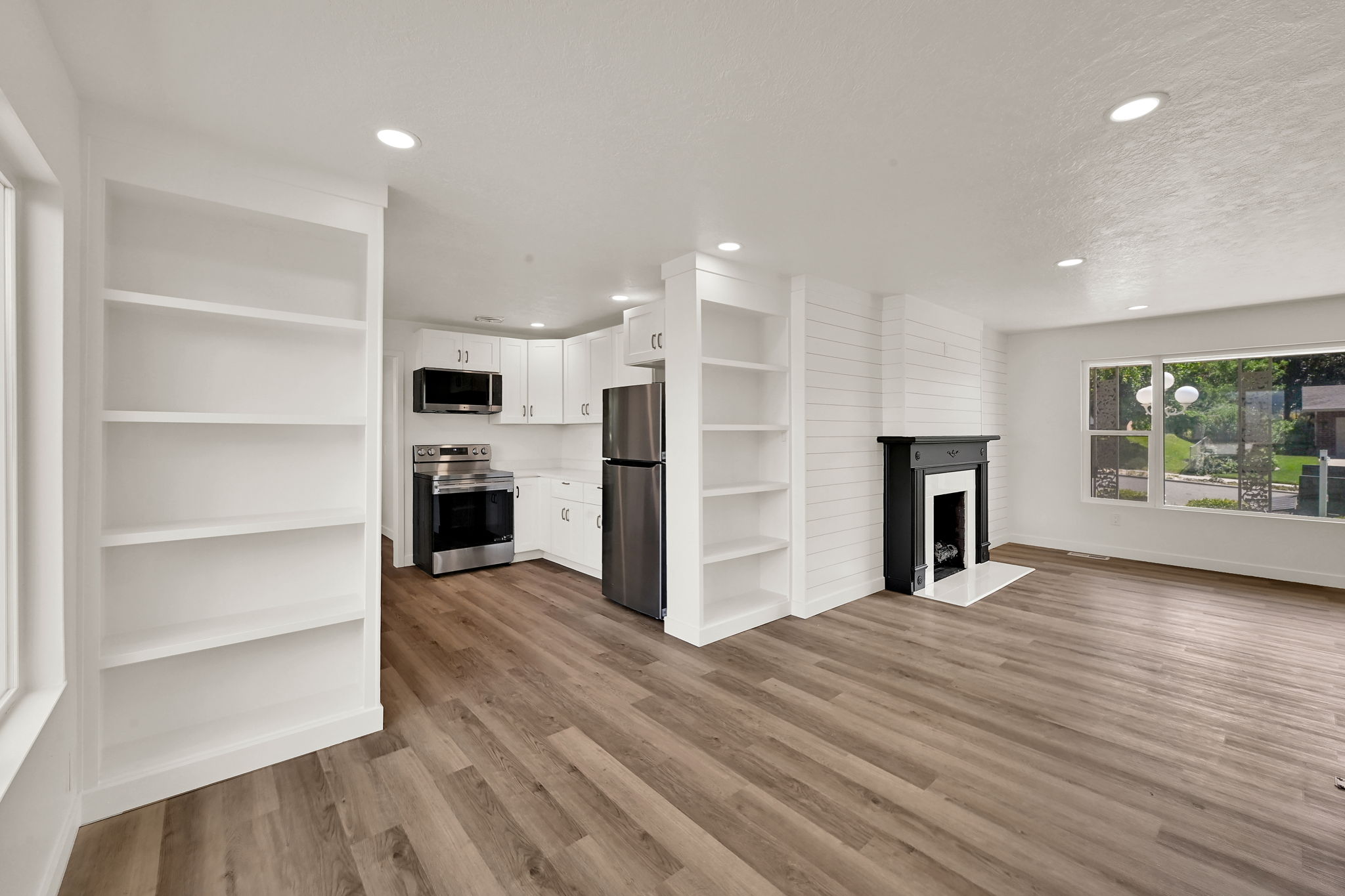 Open-concept living space featuring wood-finish flooring, recessed lighting, and a white shiplap accent wall