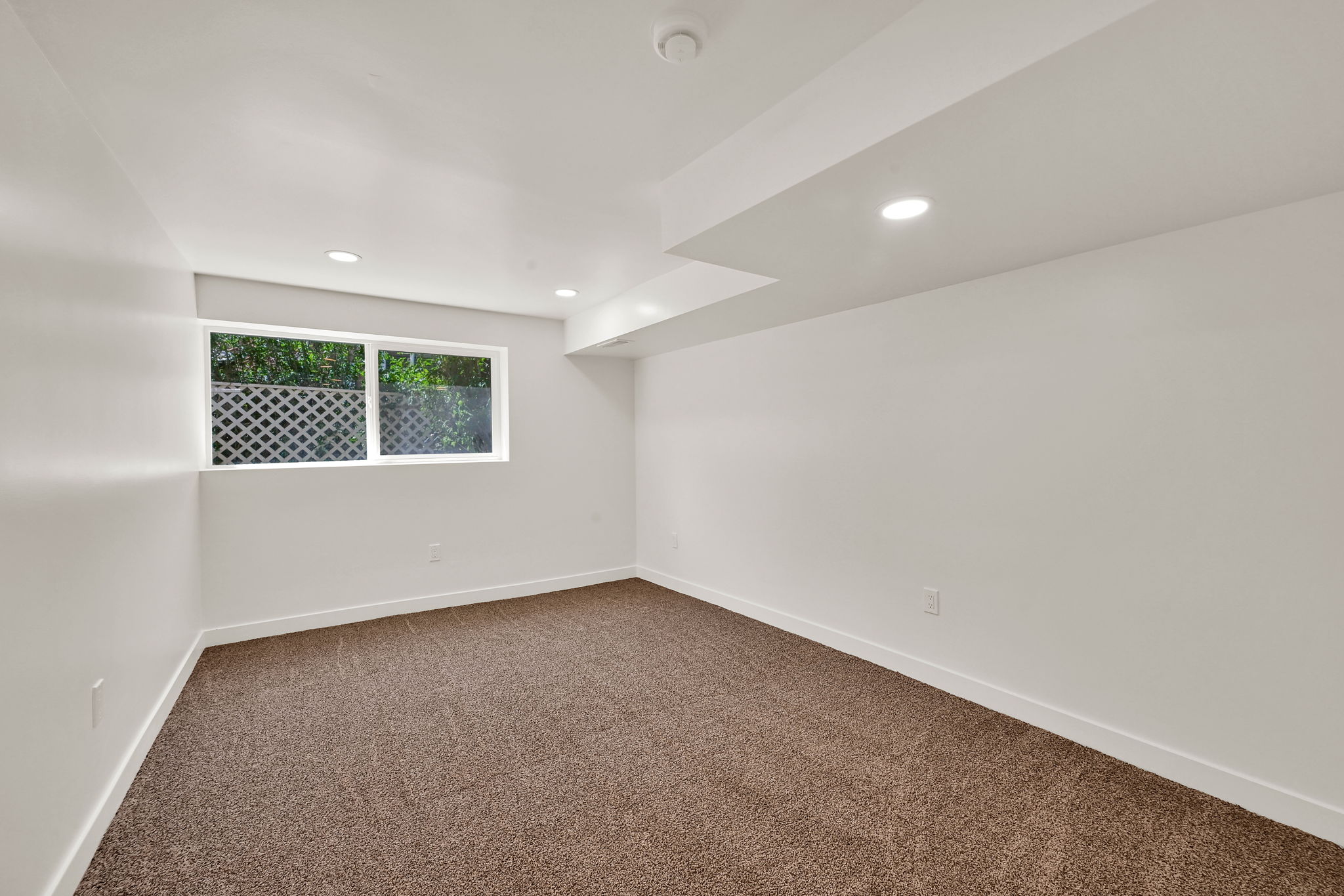 Carpeted room featuring a white window frame, recessed lighting, and white baseboards