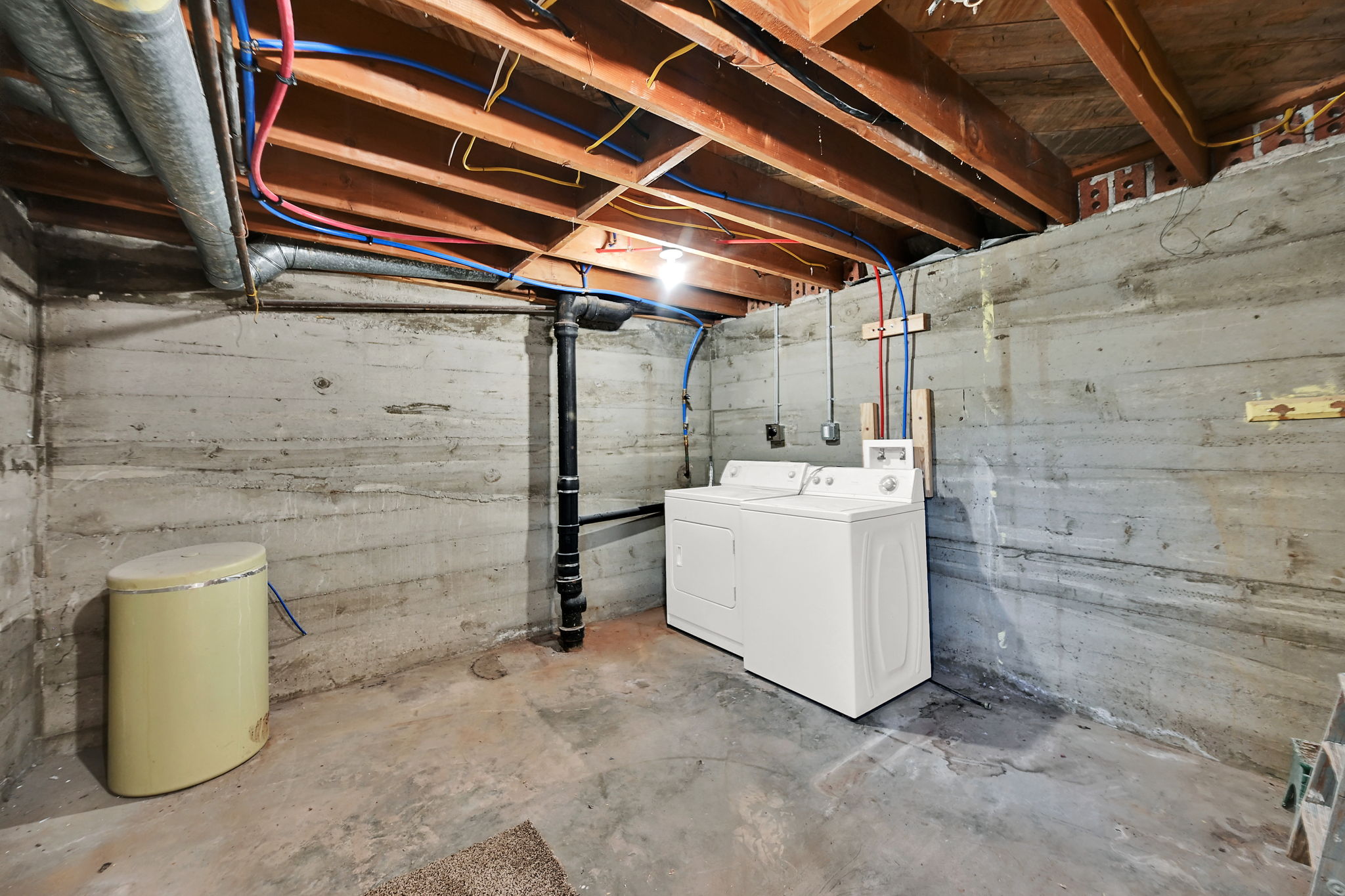Exposed wood ceiling joists and concrete foundation walls define this utility space