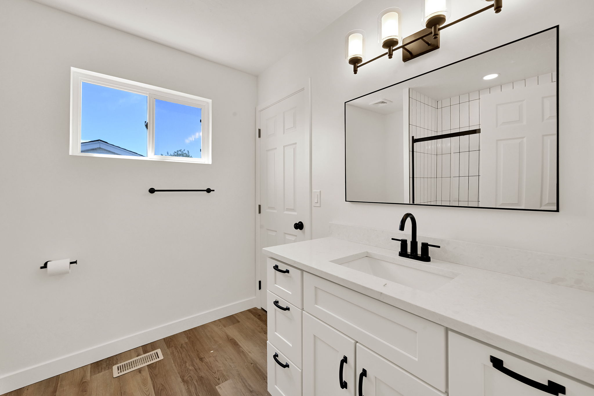 Bathroom featuring a white vanity with integrated sink, black fixtures, and a large framed mirror