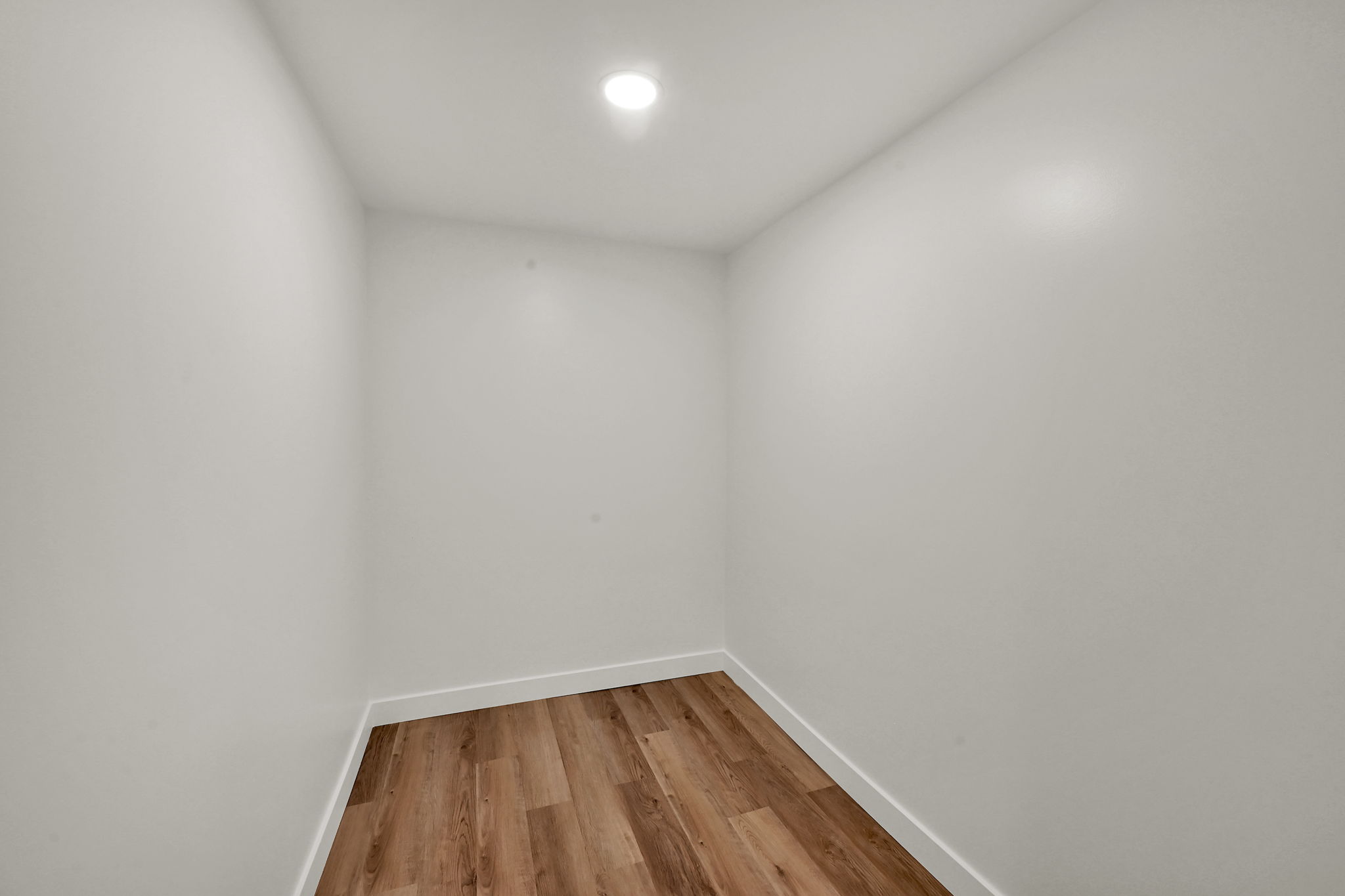 Compact room featuring wood-finish flooring, white baseboards, and a recessed ceiling light