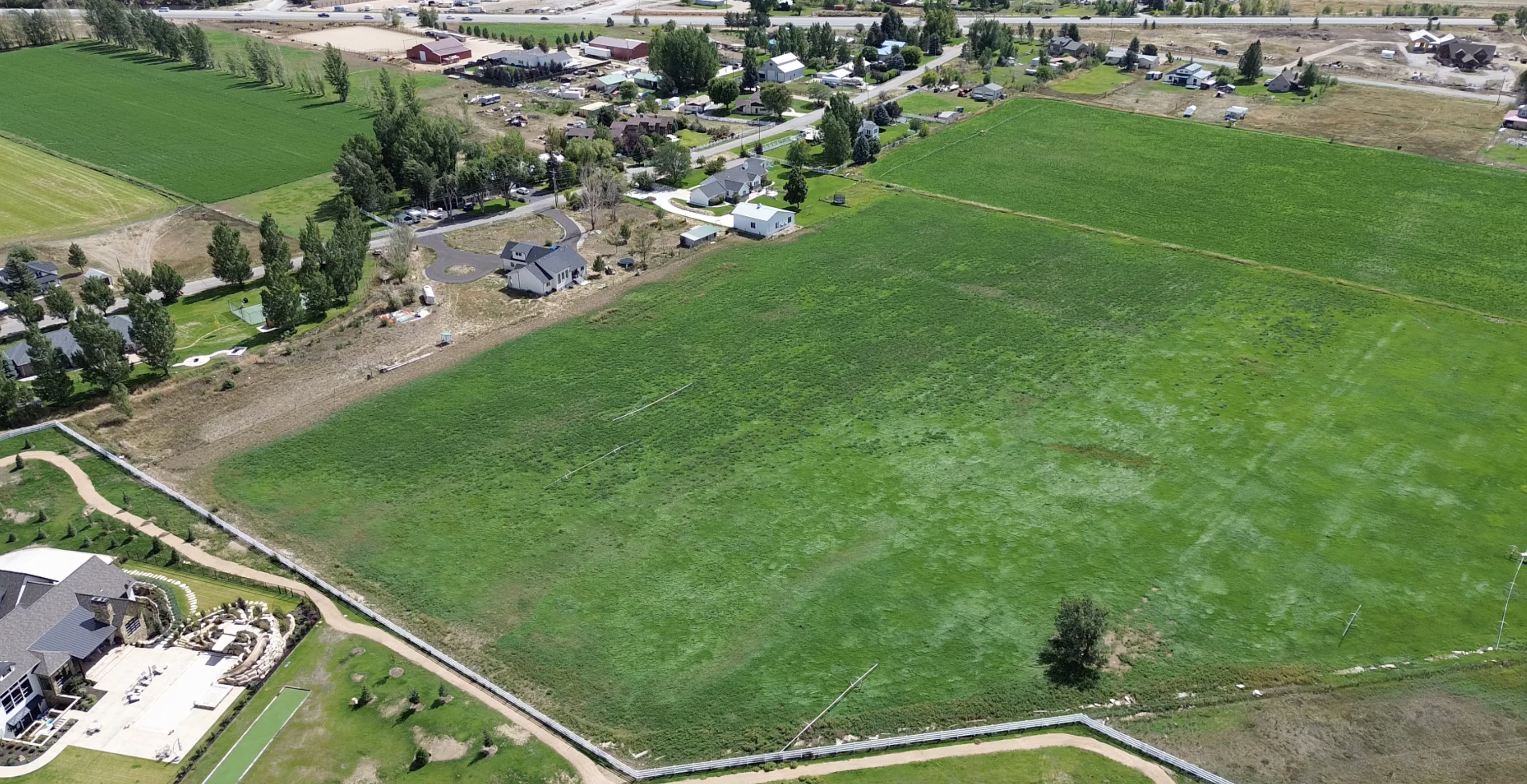 Expansive green field surrounded by residential properties and agricultural lands