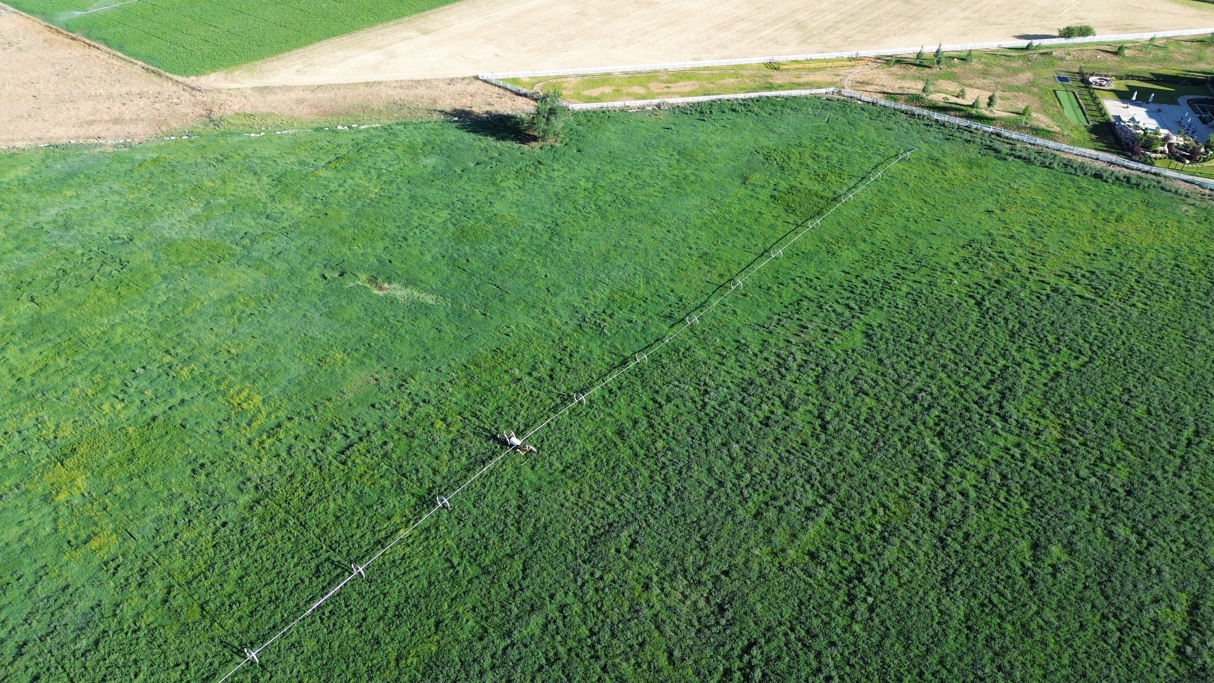 Expansive green pastureland with visible irrigation system and defined property boundaries