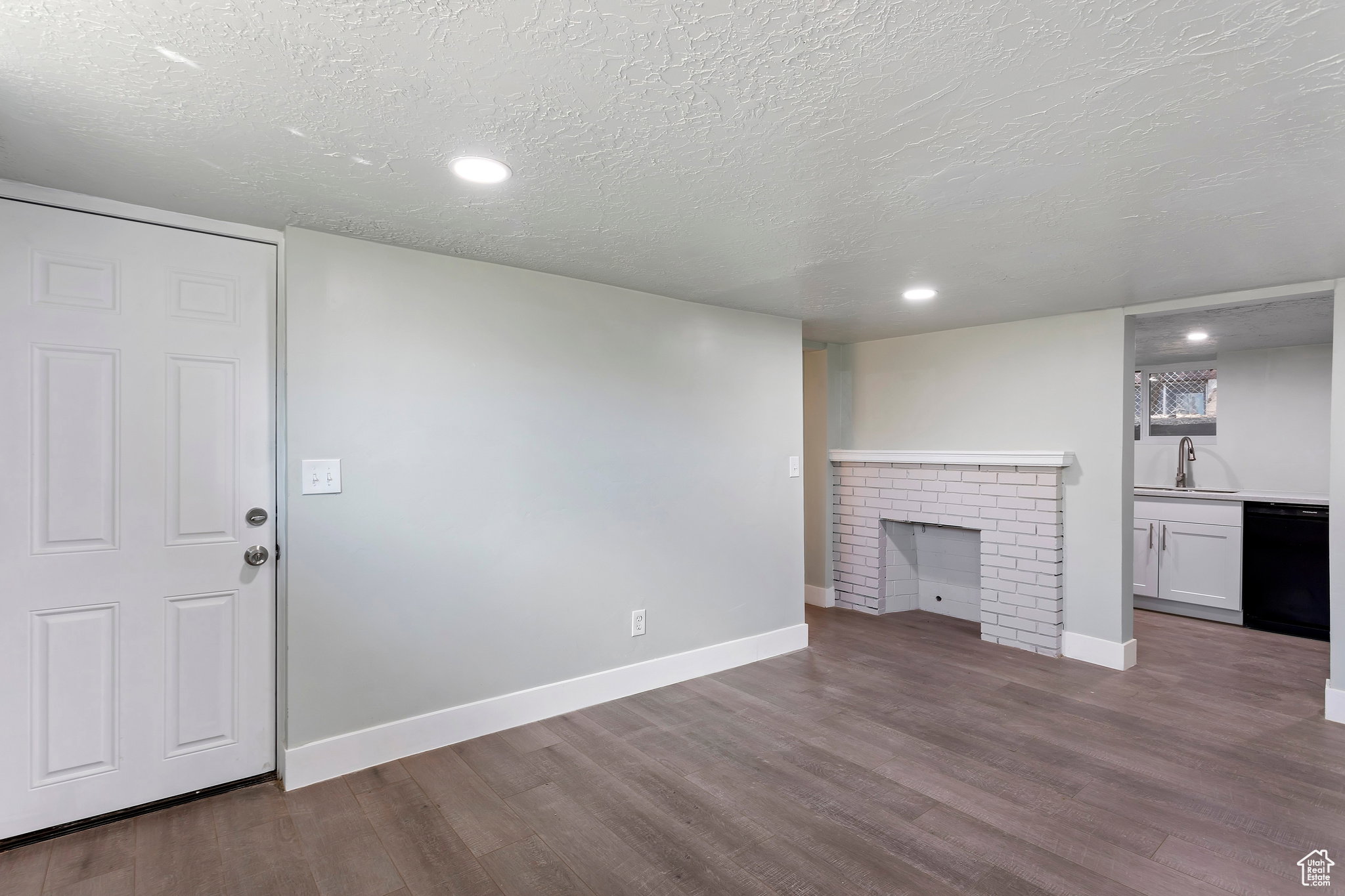 Living space featuring wood-finish flooring, recessed lighting, and a white brick fireplace with a mantel