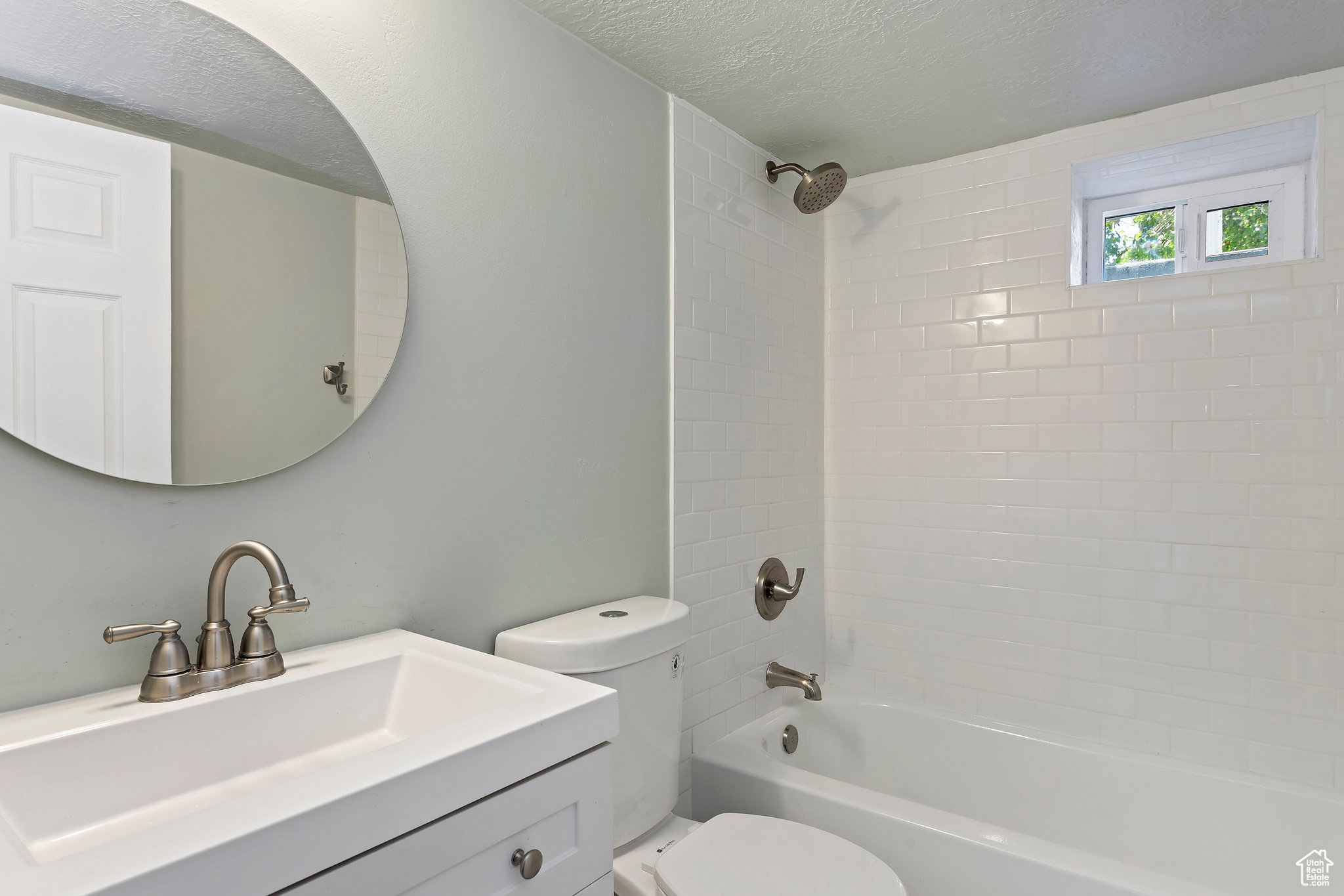 Bathroom featuring white subway tile surround, built-in bathtub, and a window for natural light