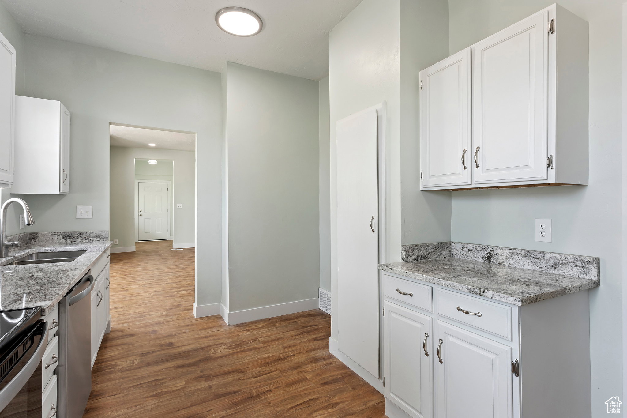 Kitchen featuring wood-finish flooring, white cabinetry, and light-toned countertops