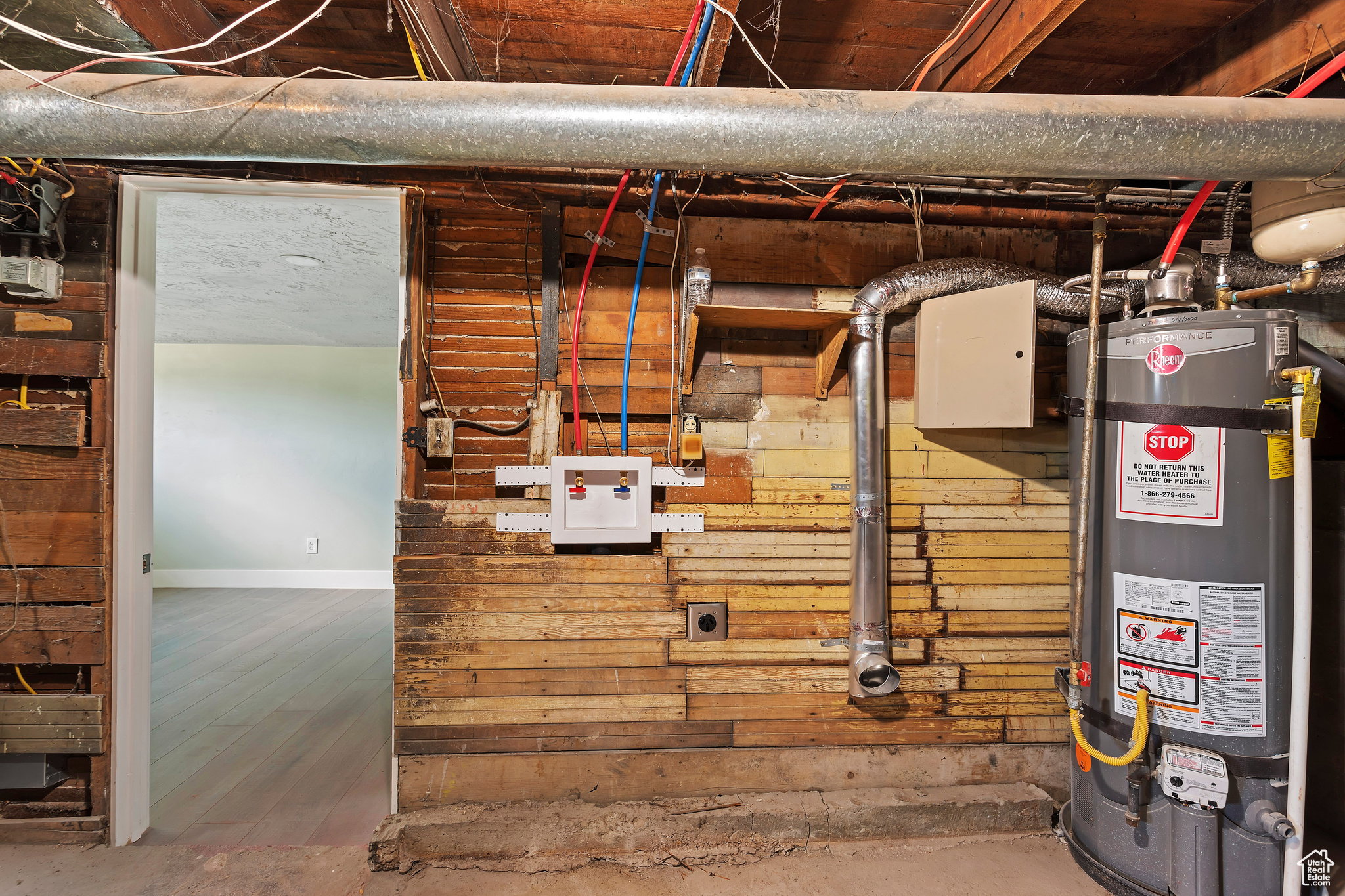 Utility space featuring a water heater, exposed wooden wall studs, and visible plumbing