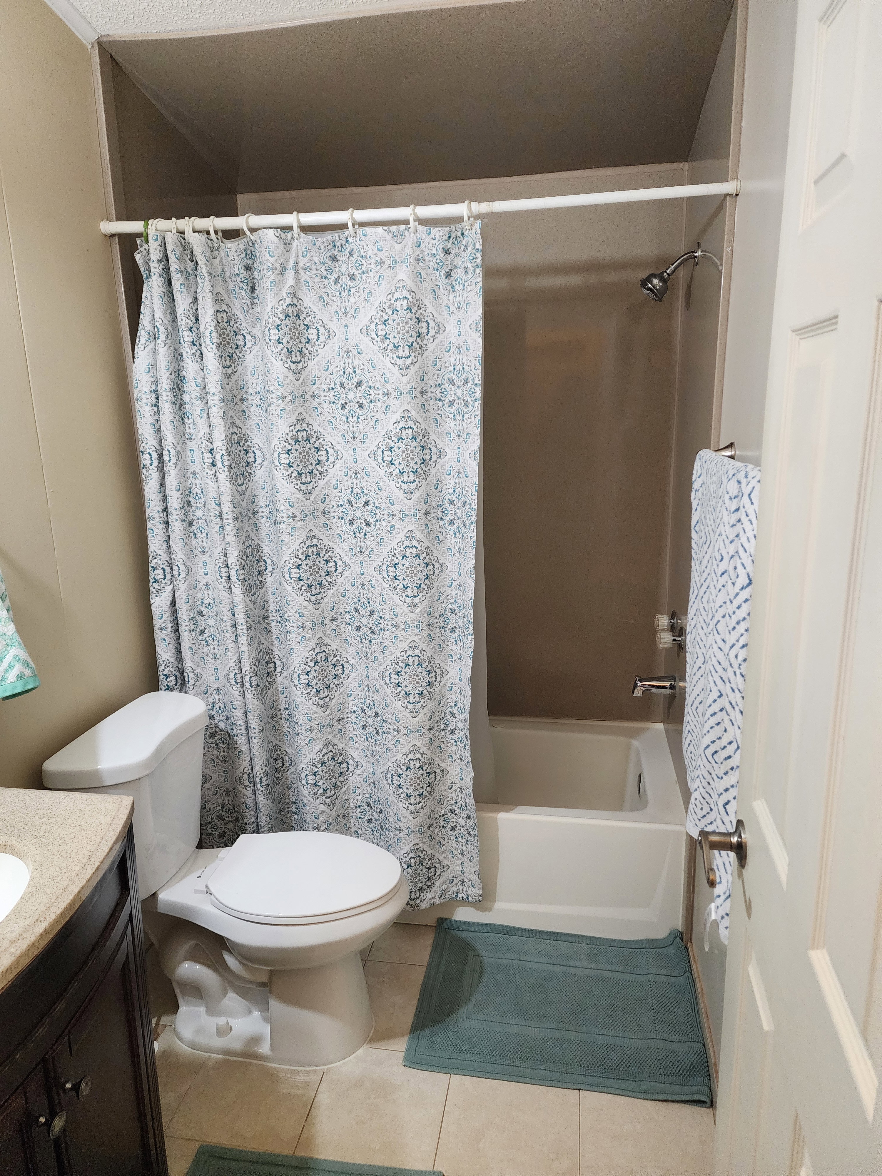 Full bath featuring a white toilet, a shower/tub combination, and a vanity with a dark wood-finish cabinet and a light-toned countertop