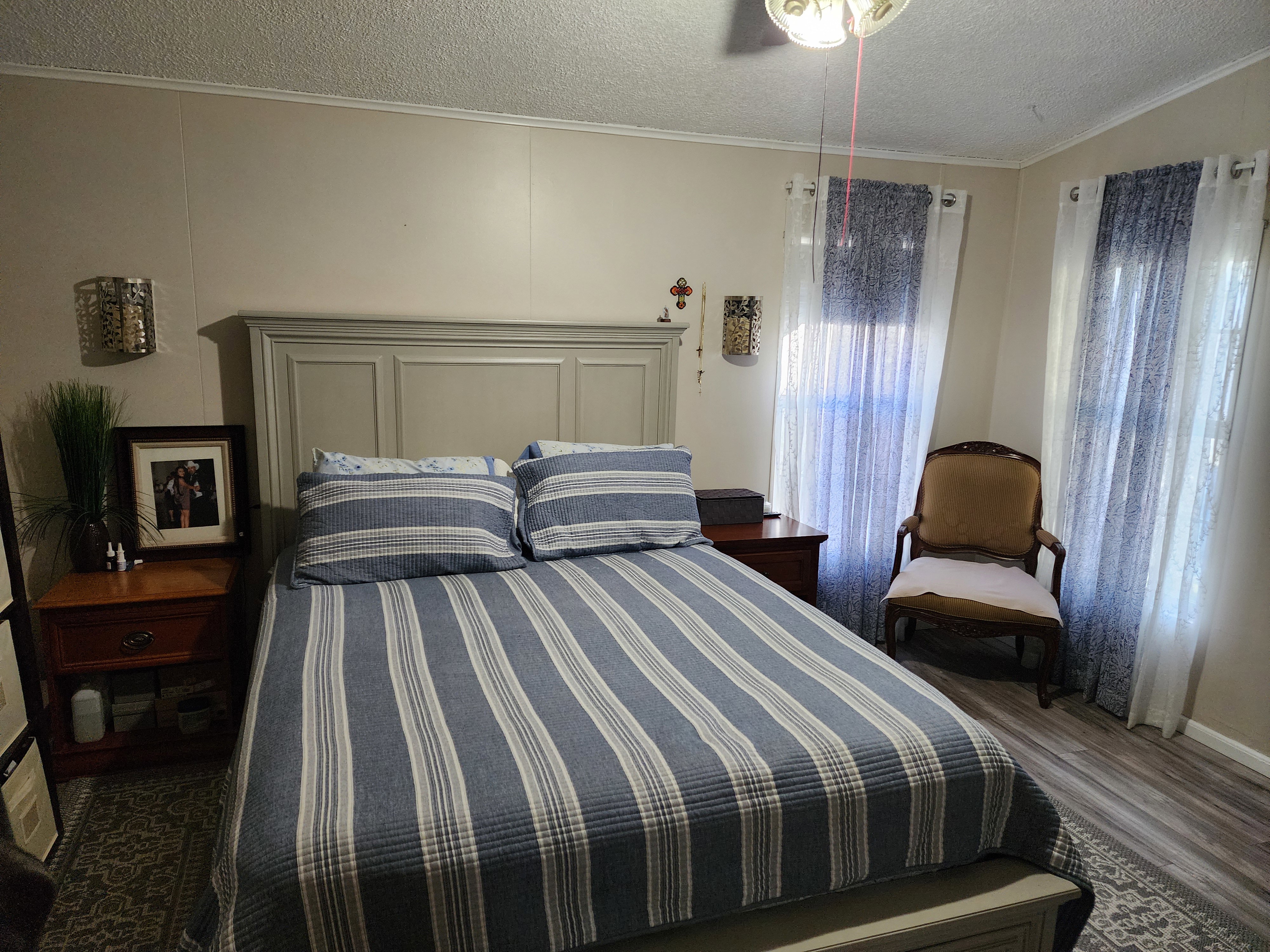 Bedroom featuring wood-finish flooring, light neutral wall paneling, and a contemporary ceiling fan with integrated lighting