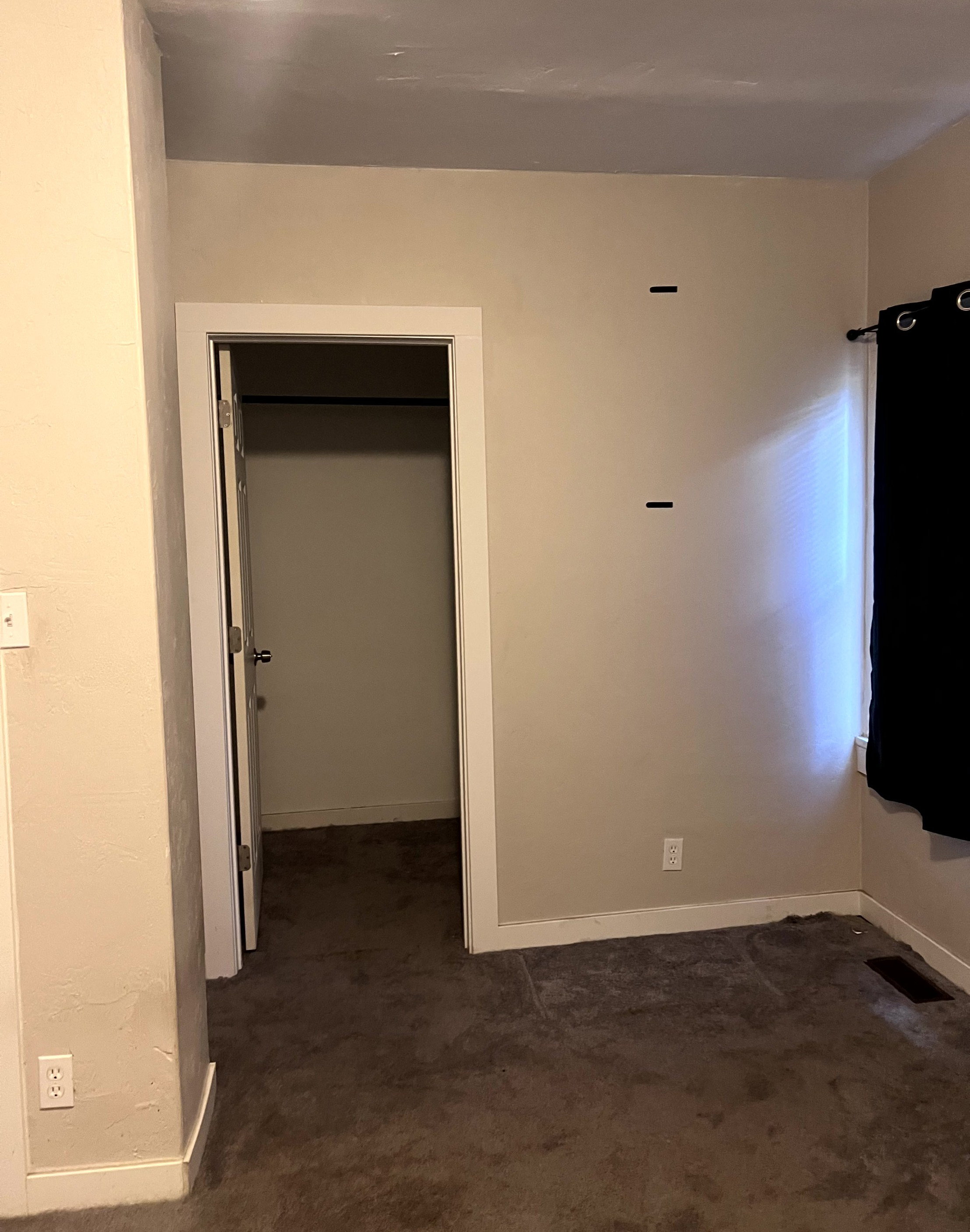 Interior room featuring a closet with an open door, neutral-toned walls, and dark carpet