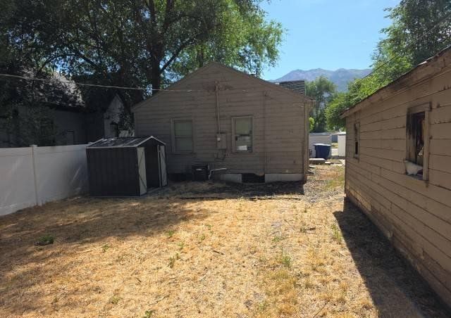Expansive backyard with a composite storage shed, white vinyl fencing, and mature trees