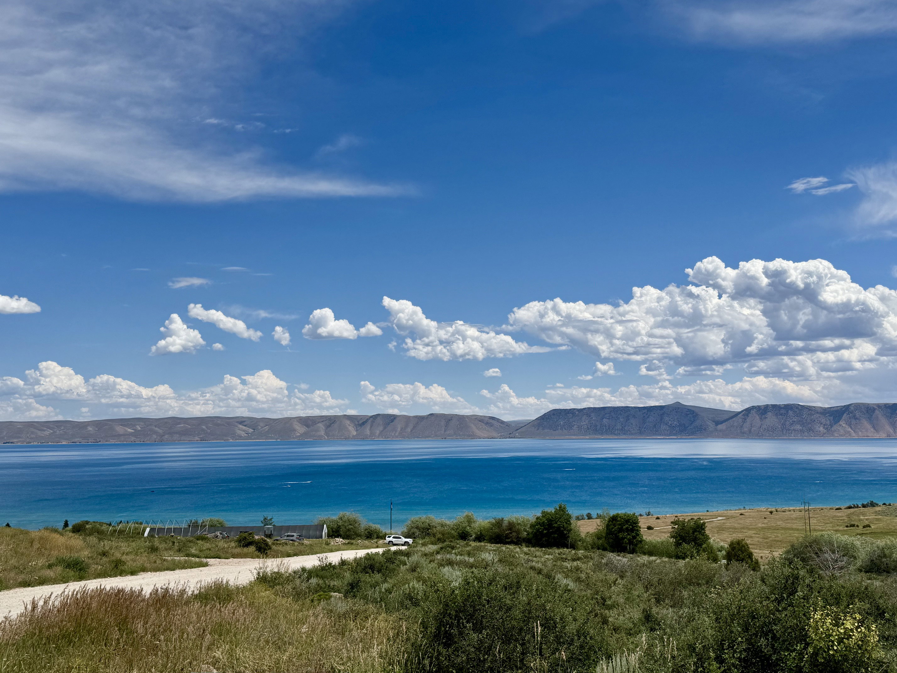 Expansive water body with distant mountains under a blue sky with scattered clouds