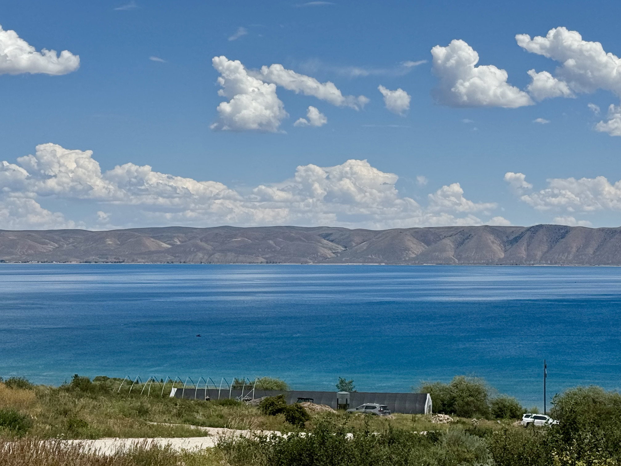 Expansive water frontage with a vibrant blue-green hue, featuring distant mountains and a natural, undeveloped shoreline